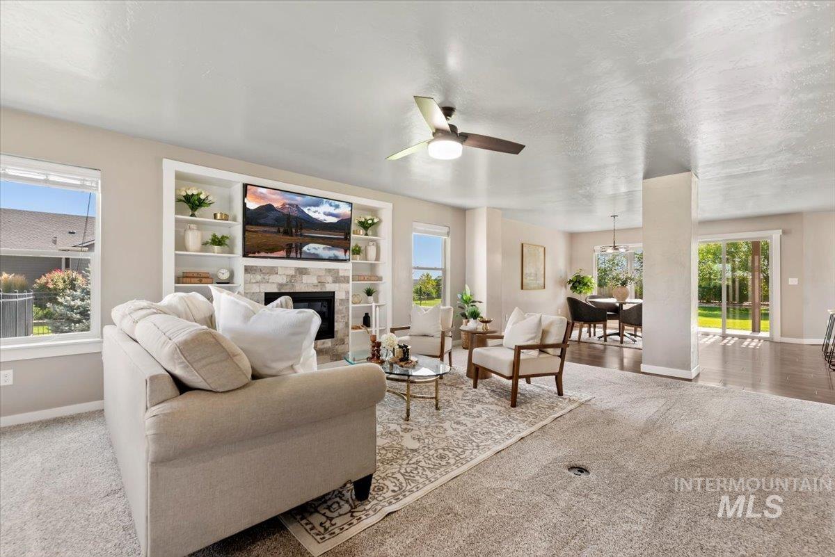 Carpeted living room with a glass covered fireplace and a ceiling fan