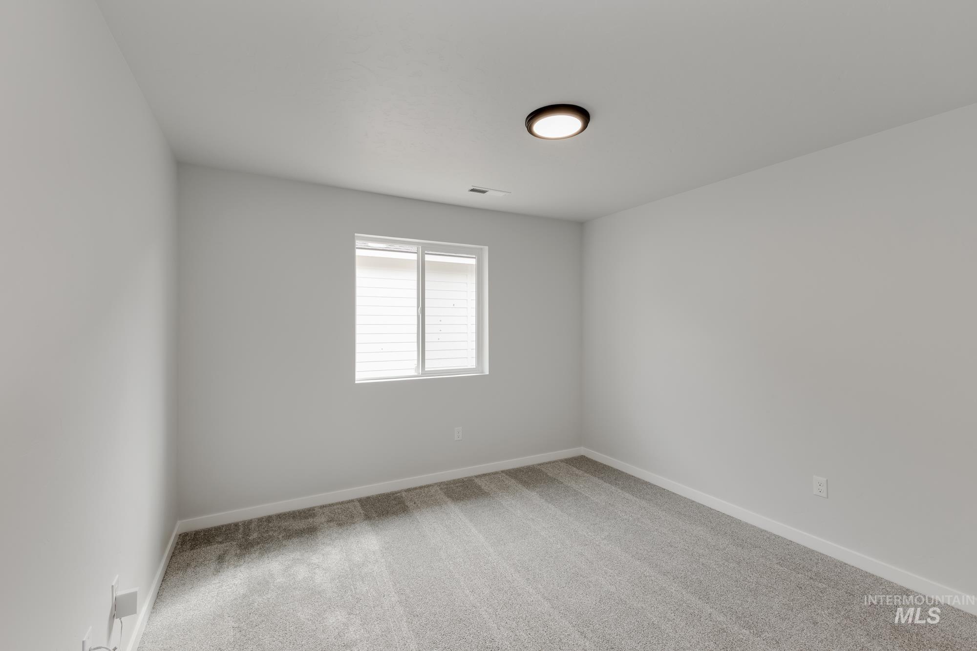 Spare room with light colored carpet and baseboards