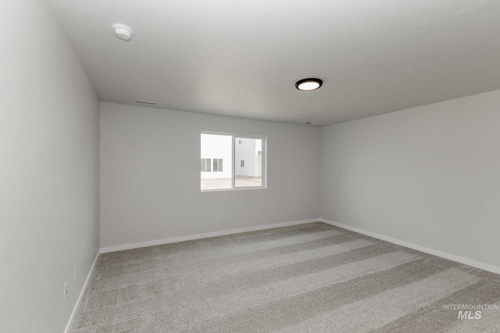 Empty room with light colored carpet and baseboards