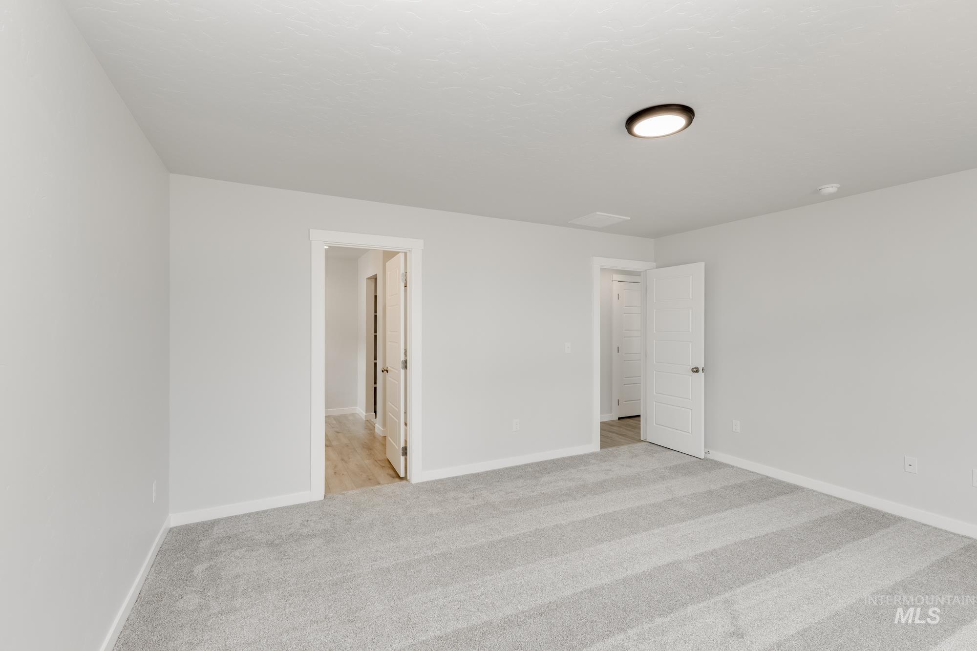 Unfurnished bedroom with light colored carpet and baseboards