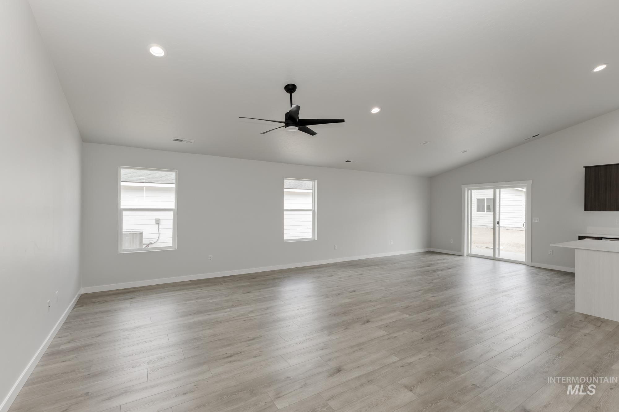 Unfurnished living room featuring healthy amount of natural light, recessed lighting, light wood finished floors, lofted ceiling, and a ceiling fan