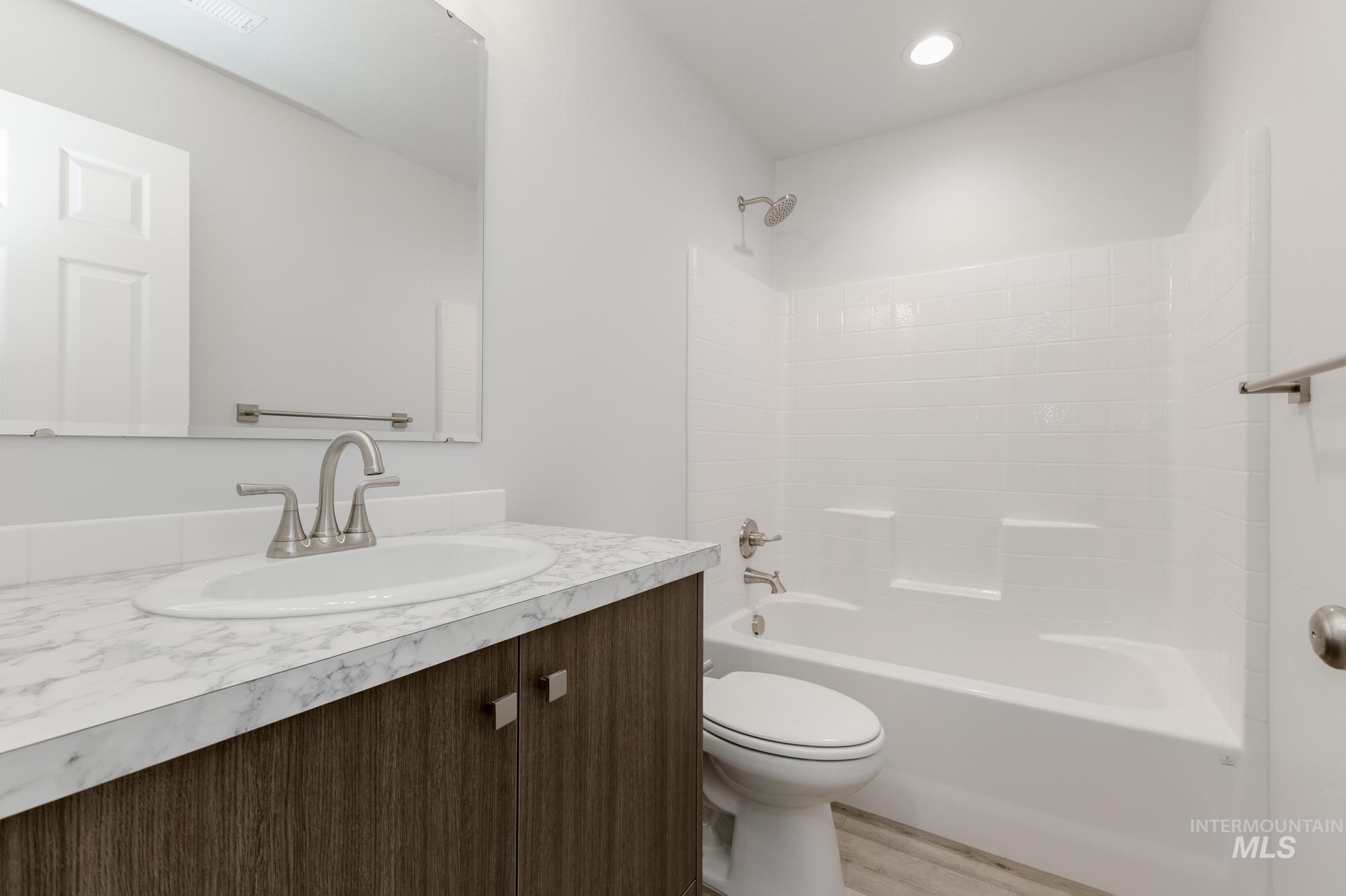 Bathroom with vanity, bathing tub / shower combination, and wood finished floors