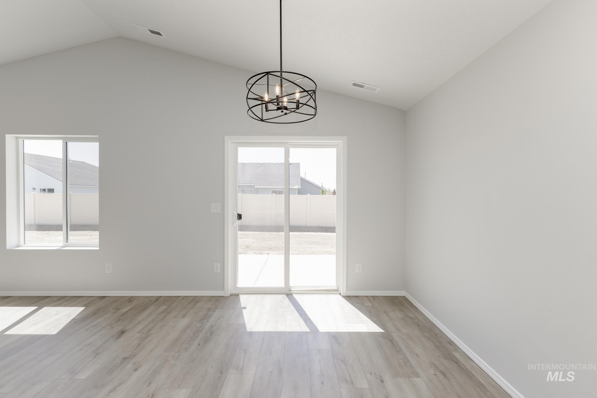 Unfurnished dining area featuring vaulted ceiling, light wood-style floors, and a chandelier