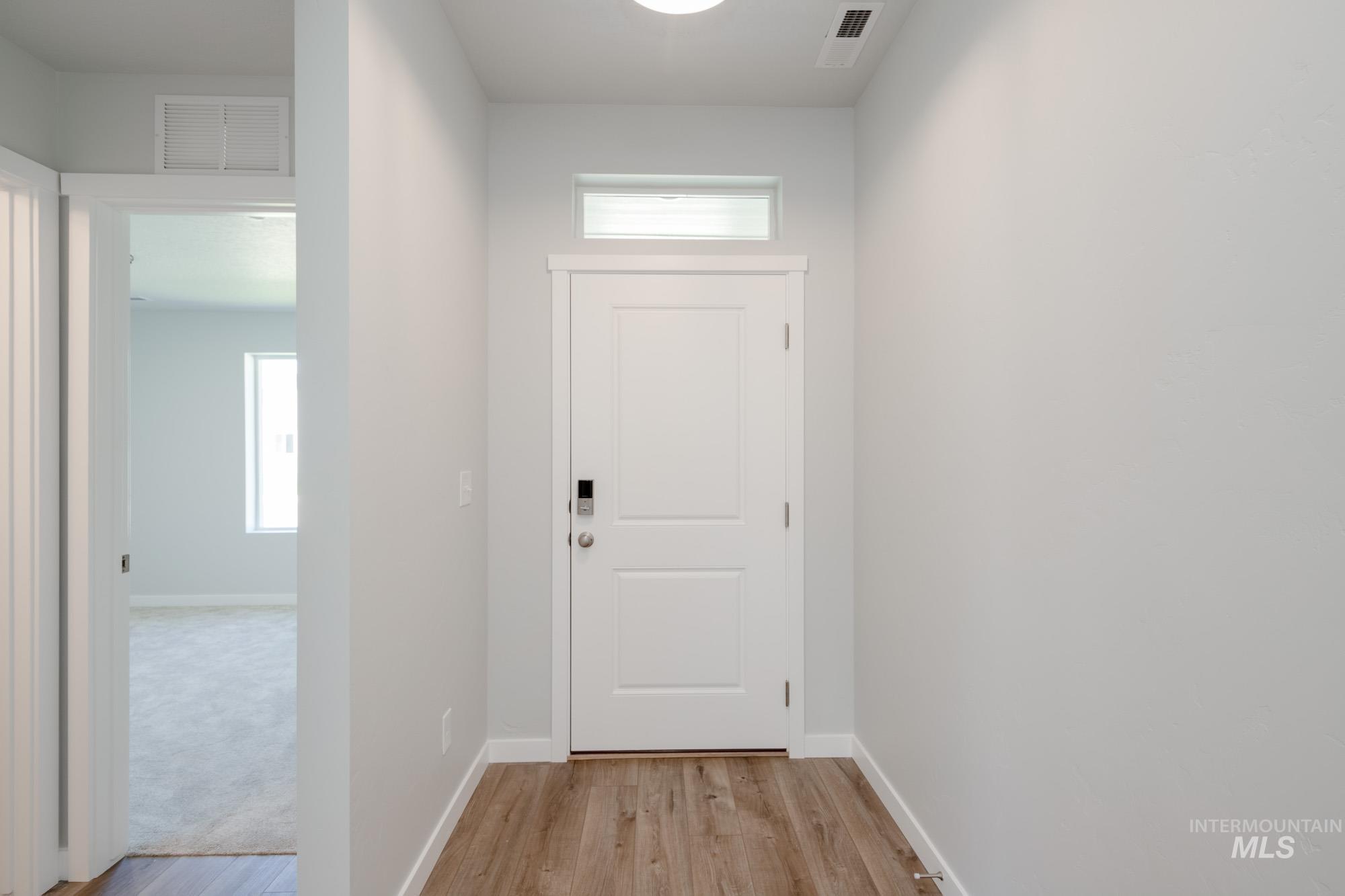 Doorway to outside featuring light wood finished floors and baseboards