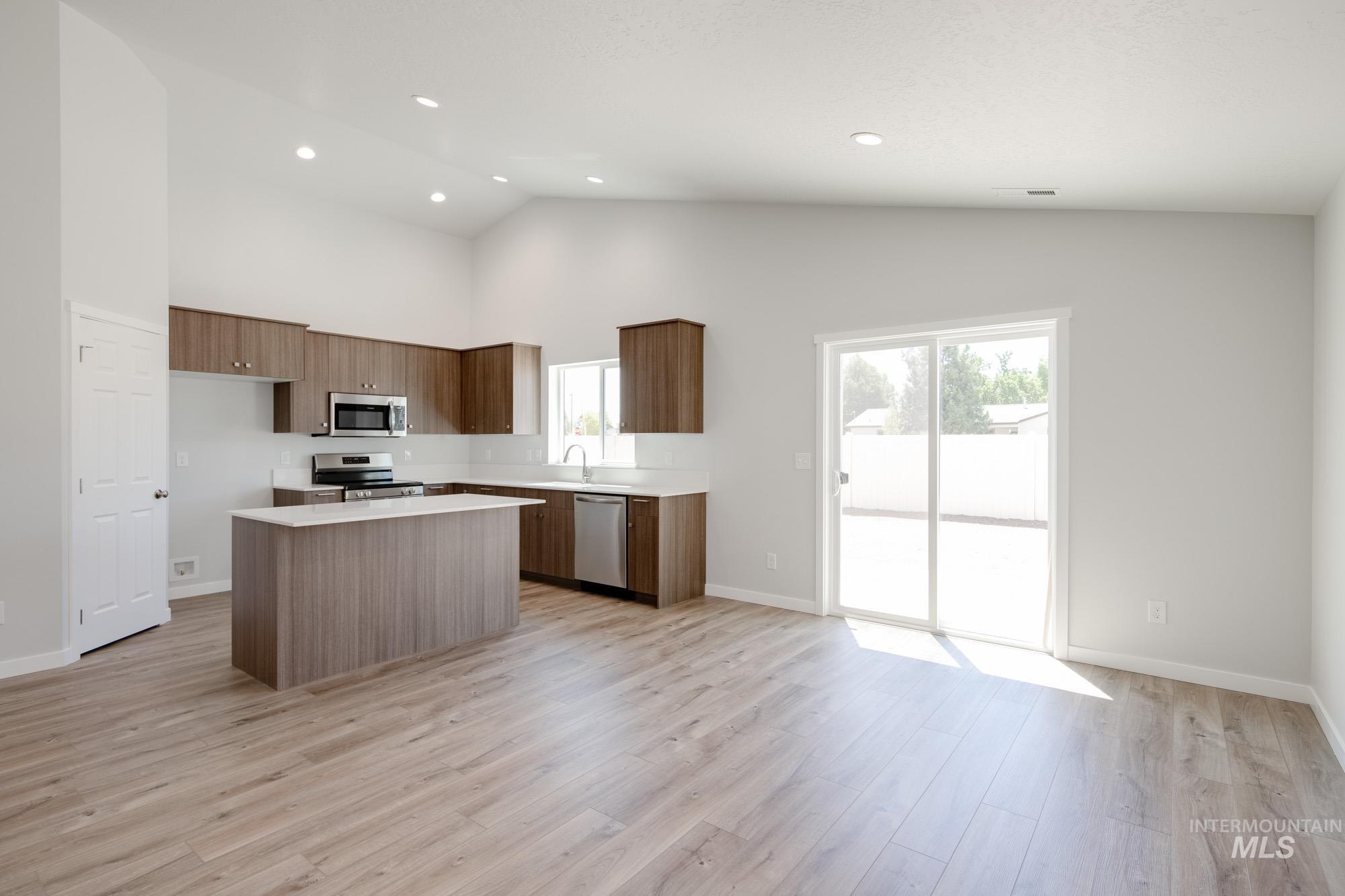 Kitchen with a kitchen island, light countertops, appliances with stainless steel finishes, light wood finished floors, and recessed lighting