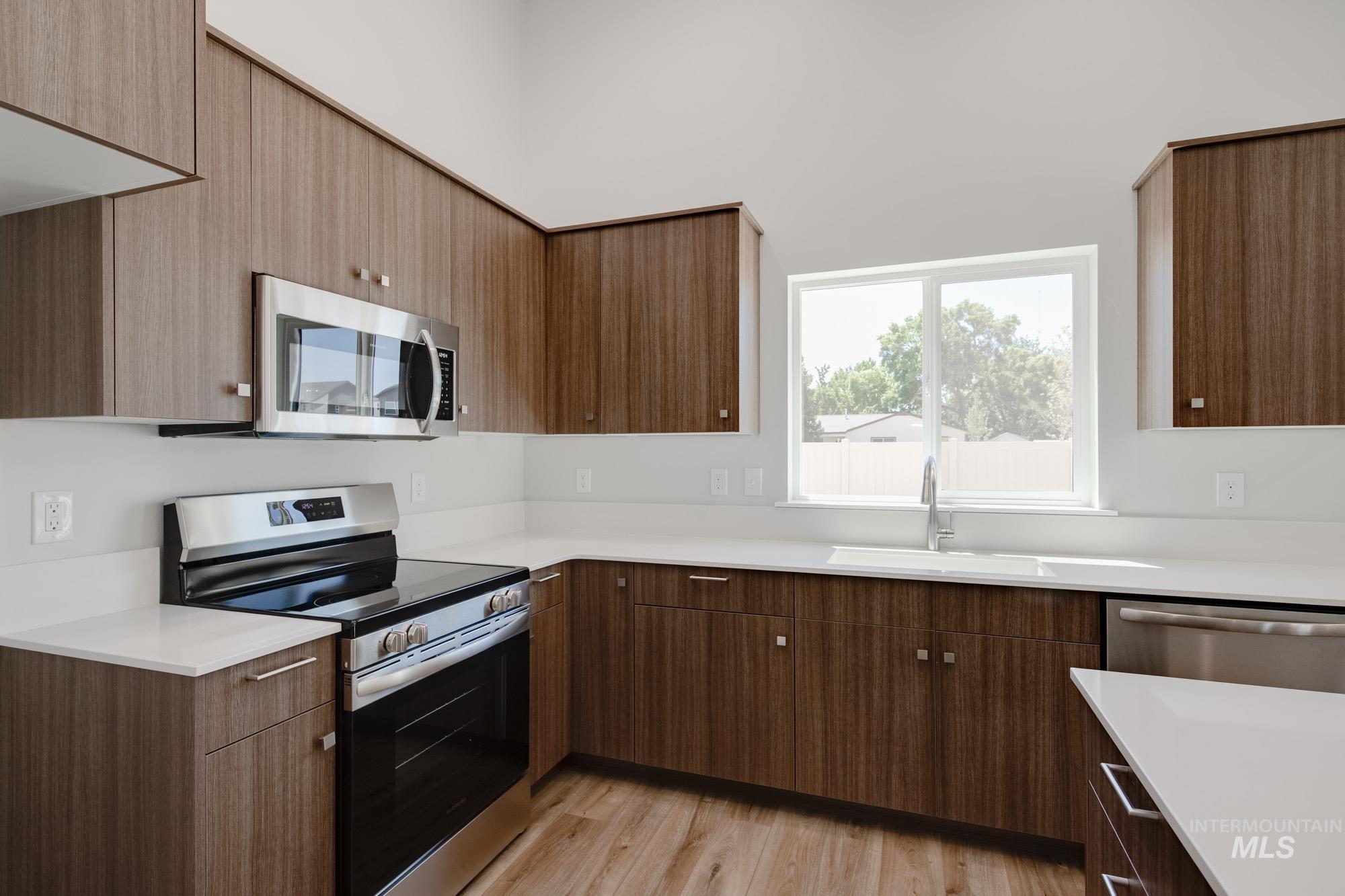 Kitchen featuring stainless steel appliances, light countertops, light wood-style floors, and modern cabinets