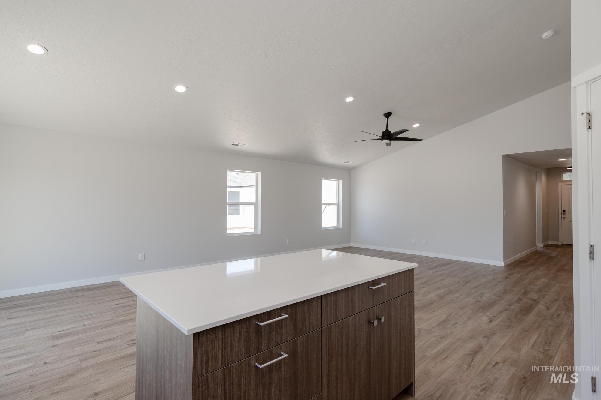 Kitchen featuring light wood-type flooring, recessed lighting, light countertops, open floor plan, and vaulted ceiling