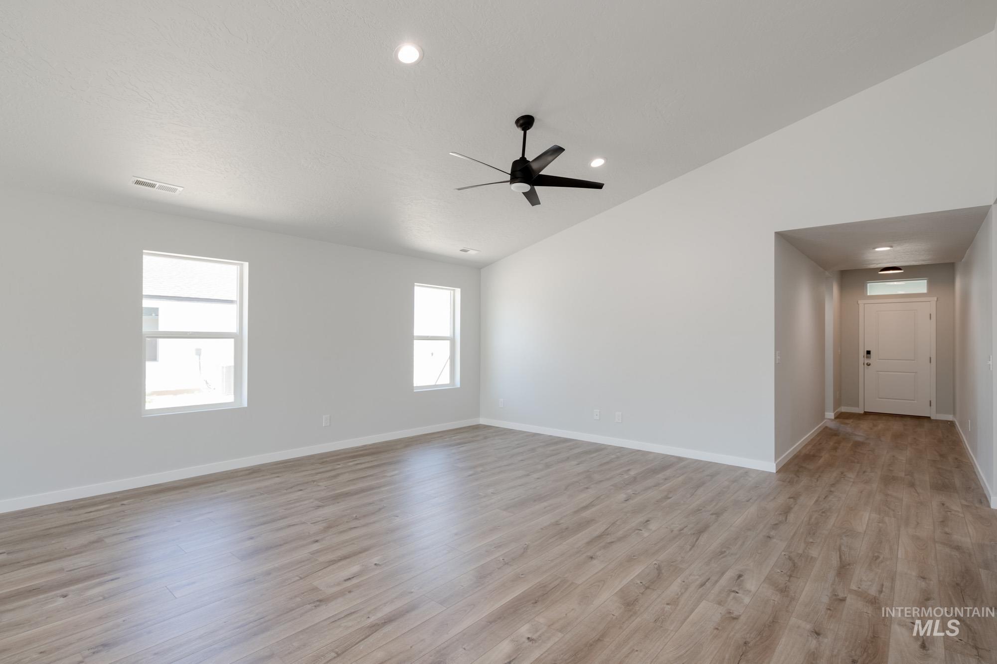 Unfurnished room featuring lofted ceiling, light wood finished floors, a ceiling fan, and recessed lighting