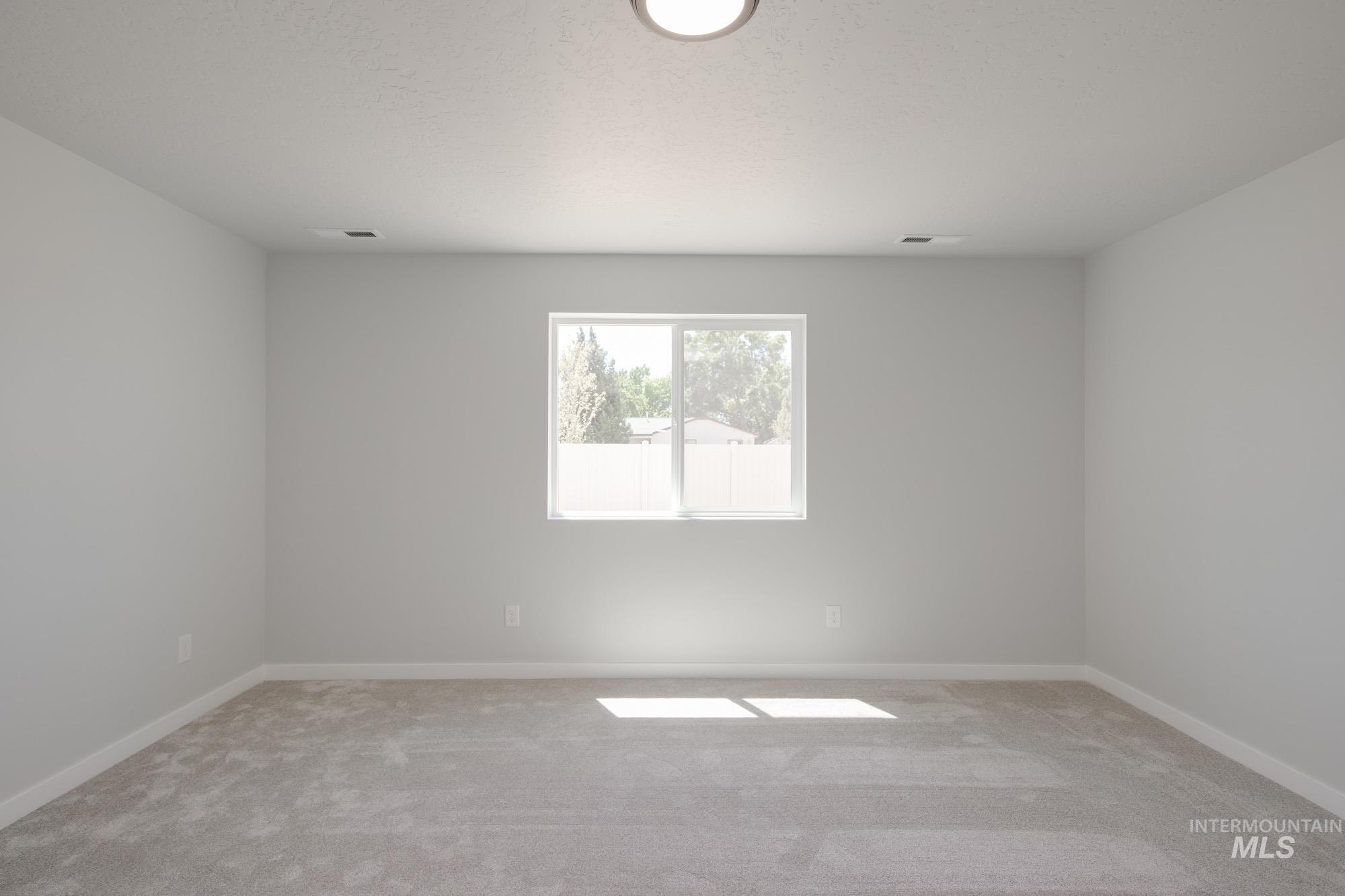 Empty room featuring light carpet and a textured ceiling