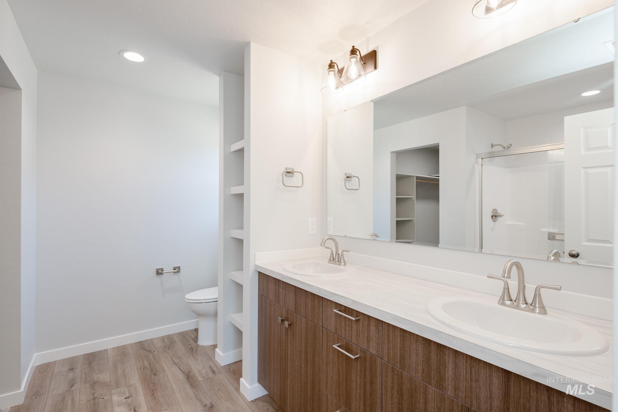 Full bathroom featuring recessed lighting, double vanity, wood finished floors, and an enclosed shower