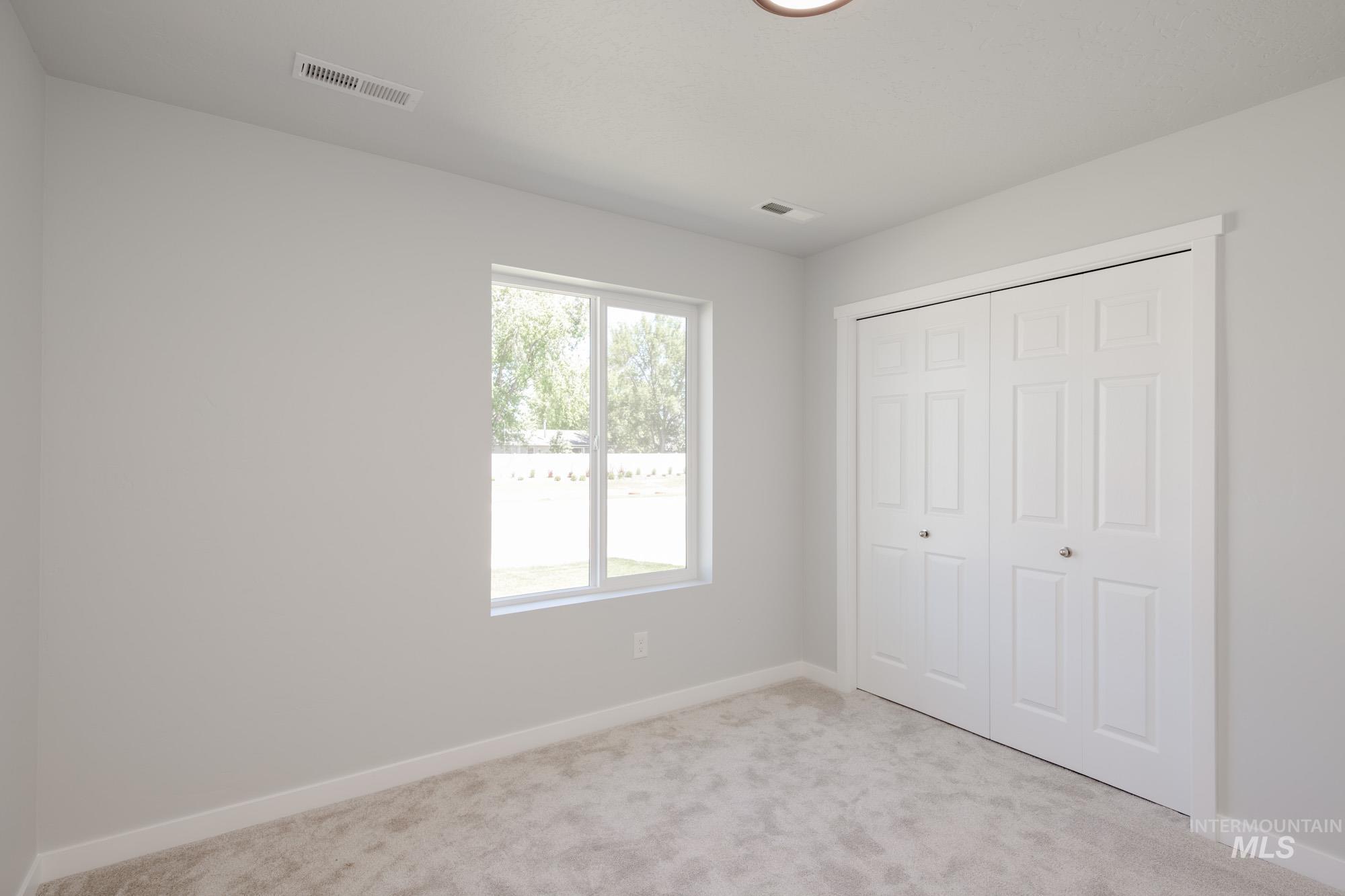 Unfurnished bedroom featuring light carpet and a closet