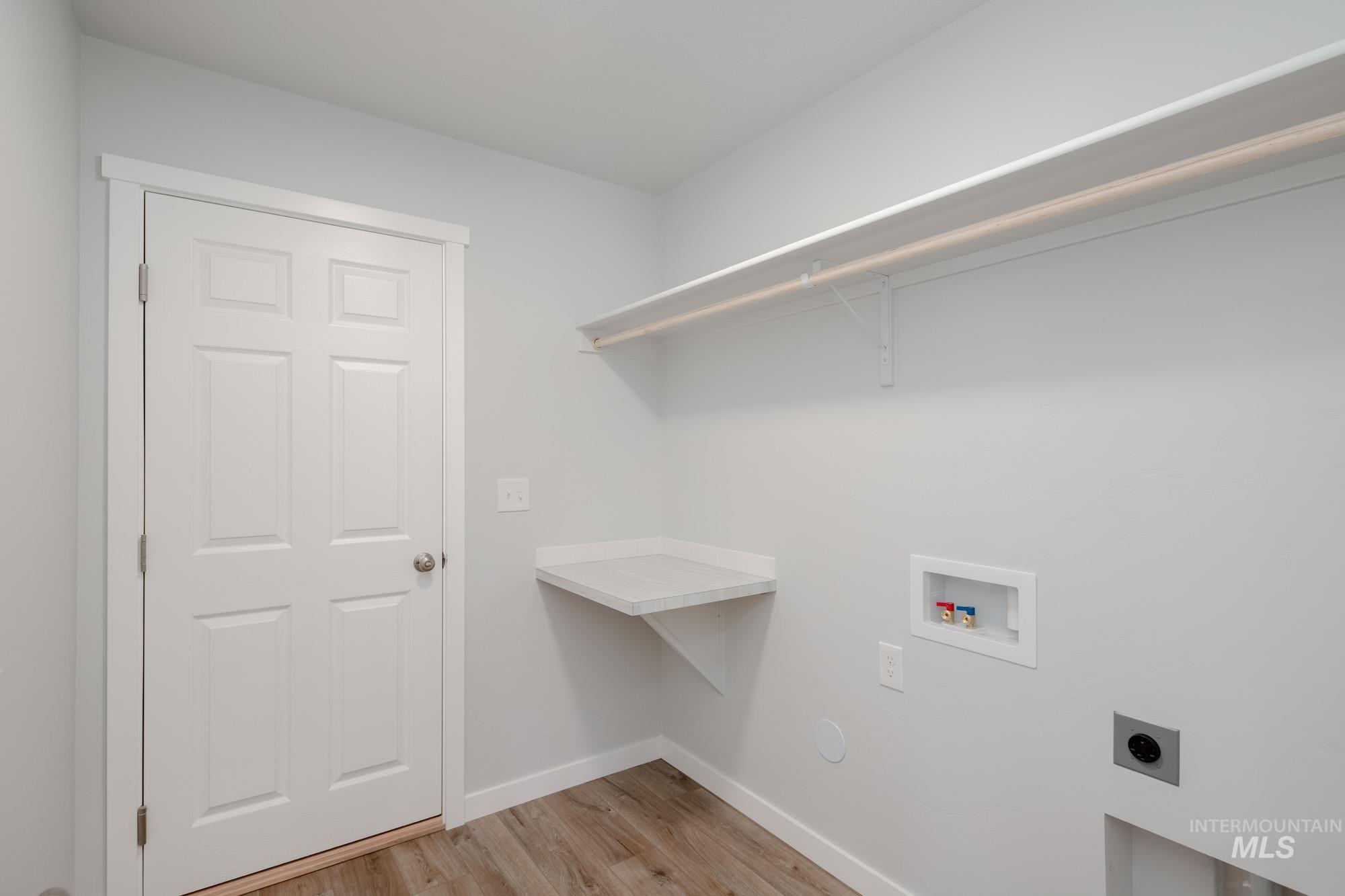 Washroom with electric dryer hookup, washer hookup, and light wood-style flooring