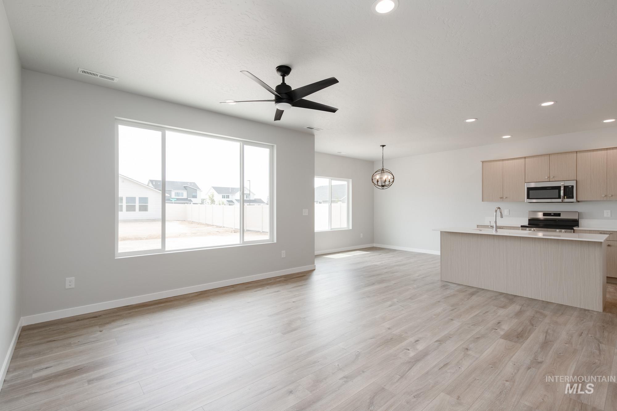 Kitchen featuring open floor plan, a chandelier, a ceiling fan, light countertops, and recessed lighting