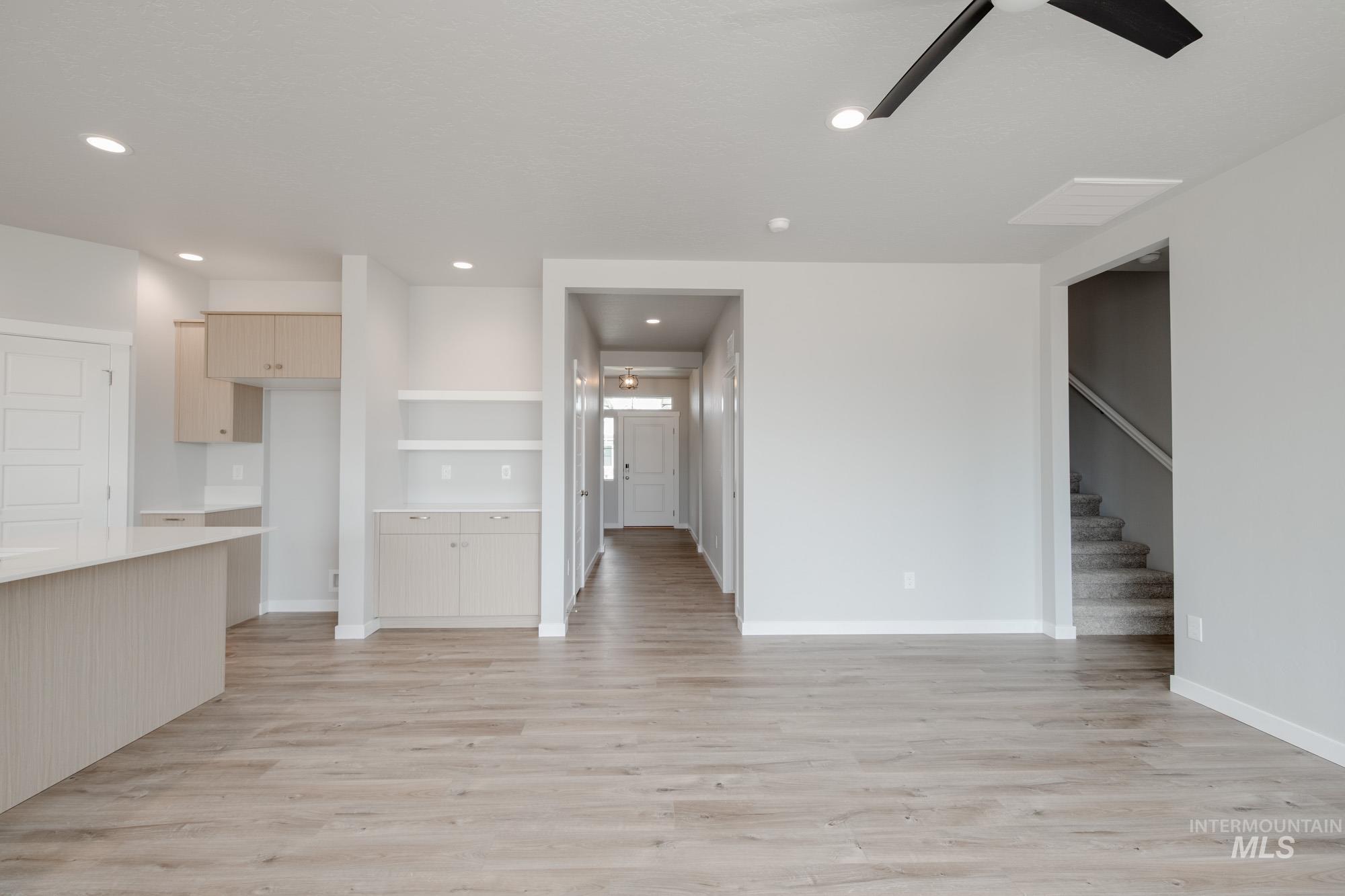 Unfurnished living room with light wood finished floors, stairs, and recessed lighting