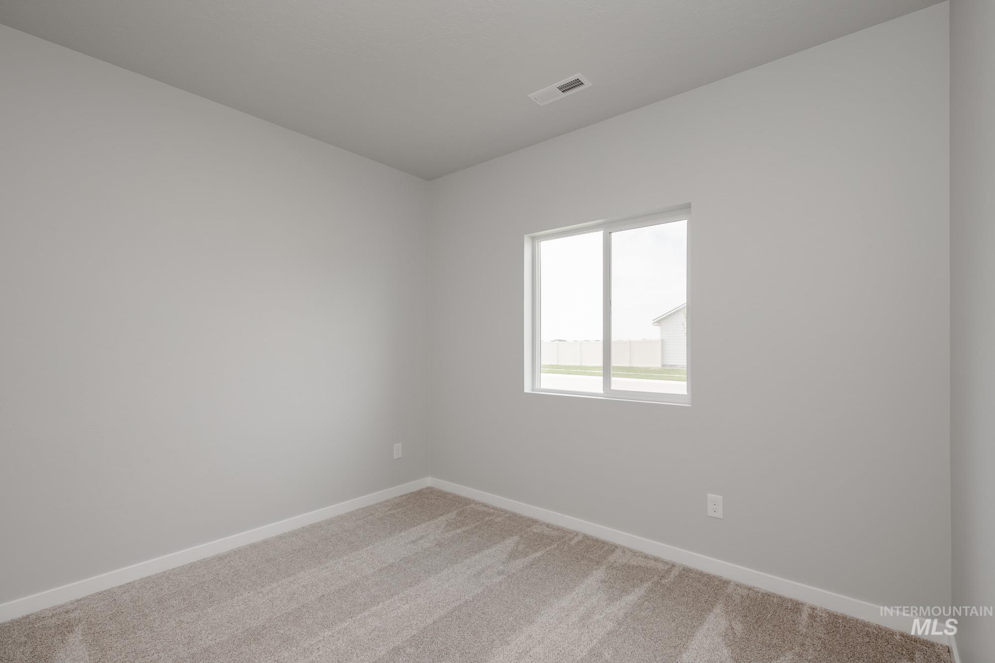 Empty room featuring light colored carpet and baseboards
