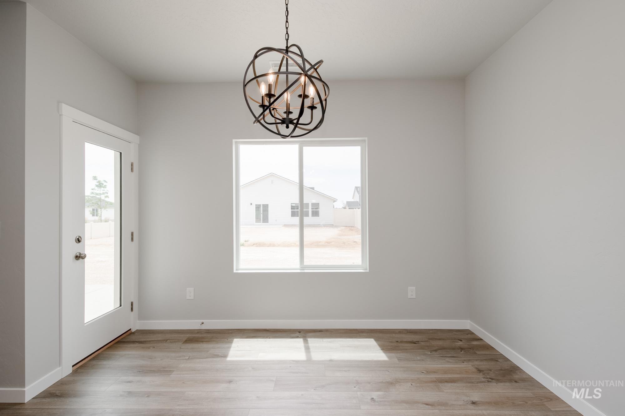 Unfurnished dining area featuring light wood-type flooring and a chandelier