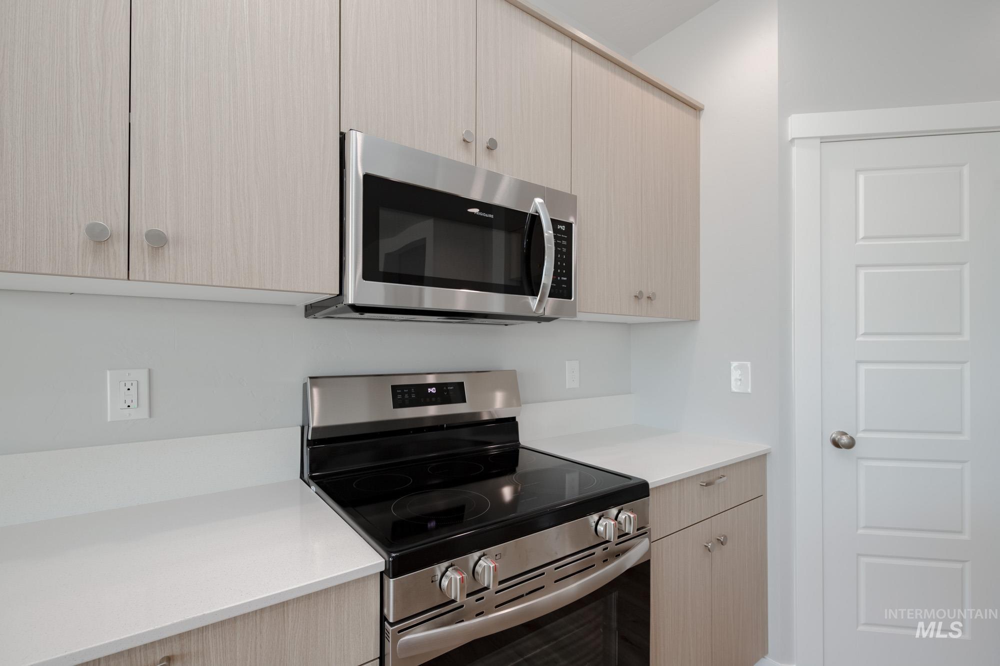 Kitchen featuring stainless steel appliances, light countertops, and light brown cabinets