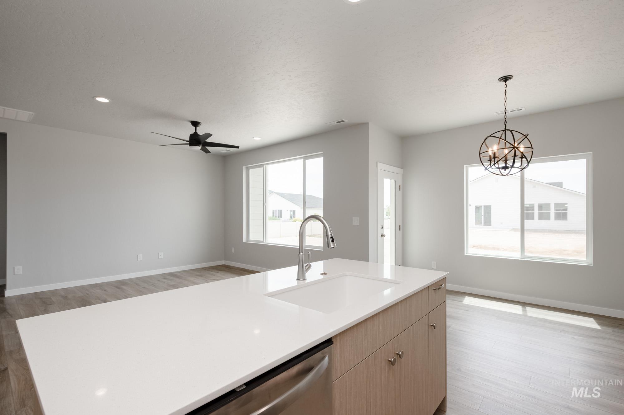 Kitchen featuring light wood-style flooring, light countertops, stainless steel dishwasher, pendant lighting, and recessed lighting