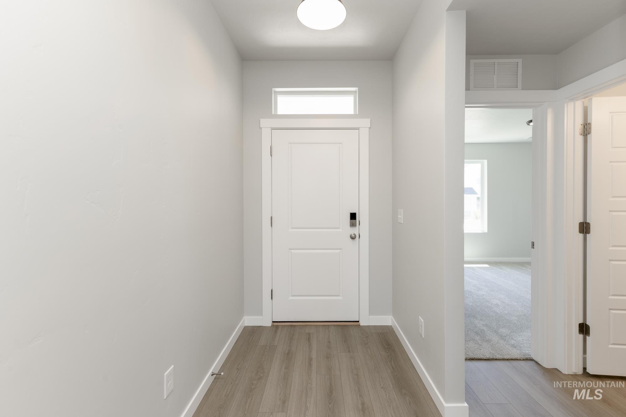 Doorway to outside featuring light wood-style flooring and baseboards