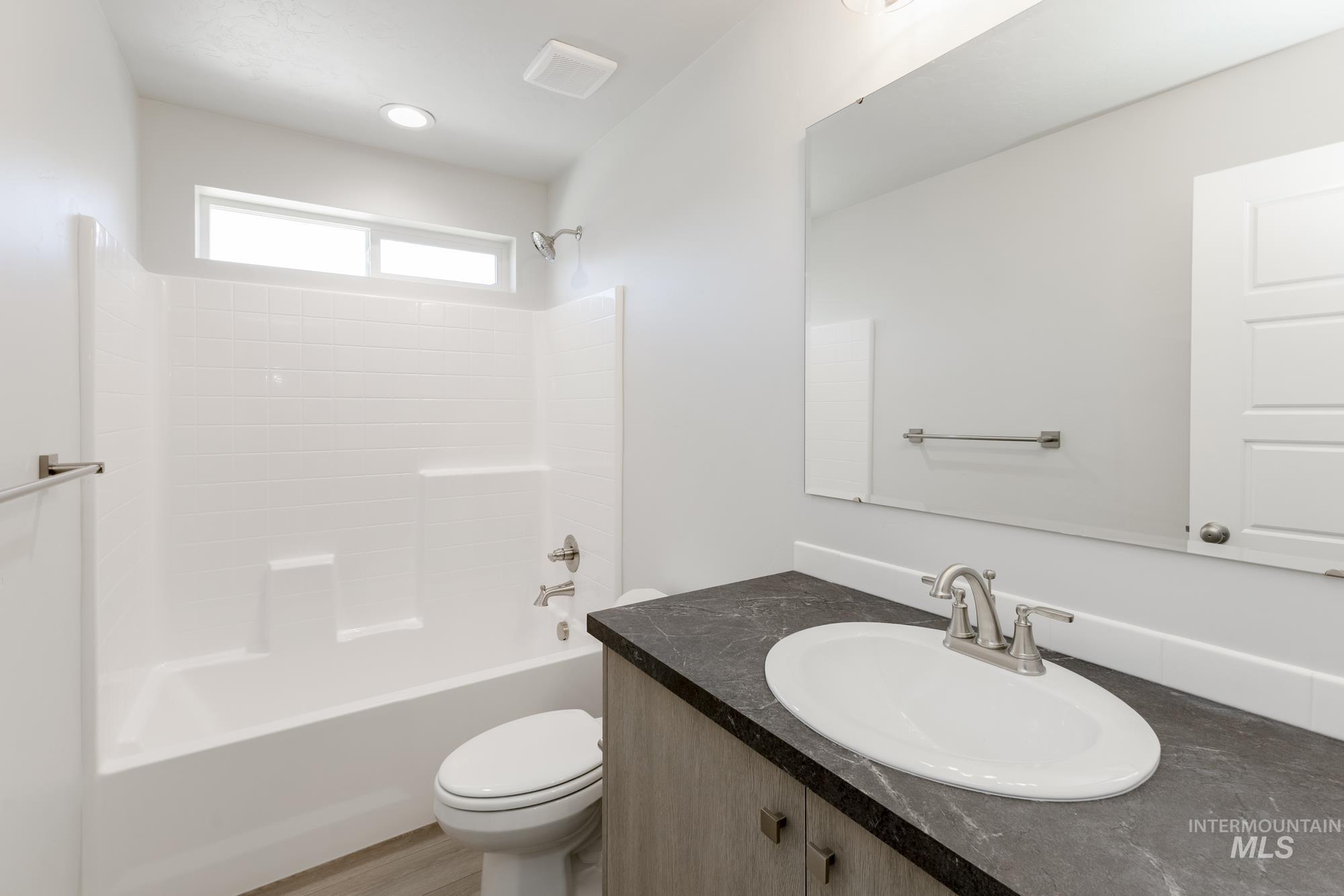 Bathroom featuring vanity, shower / tub combination, and wood finished floors