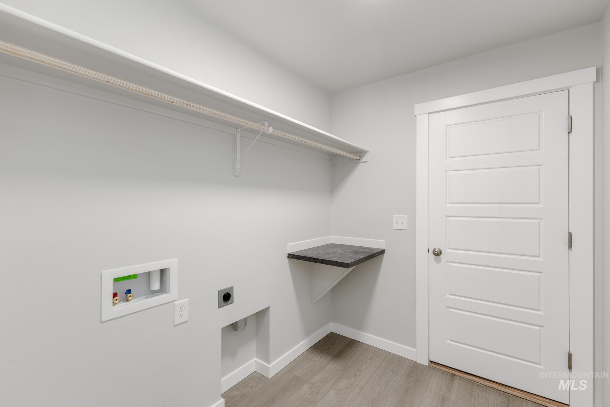 Laundry room with electric dryer hookup, washer hookup, and light wood finished floors
