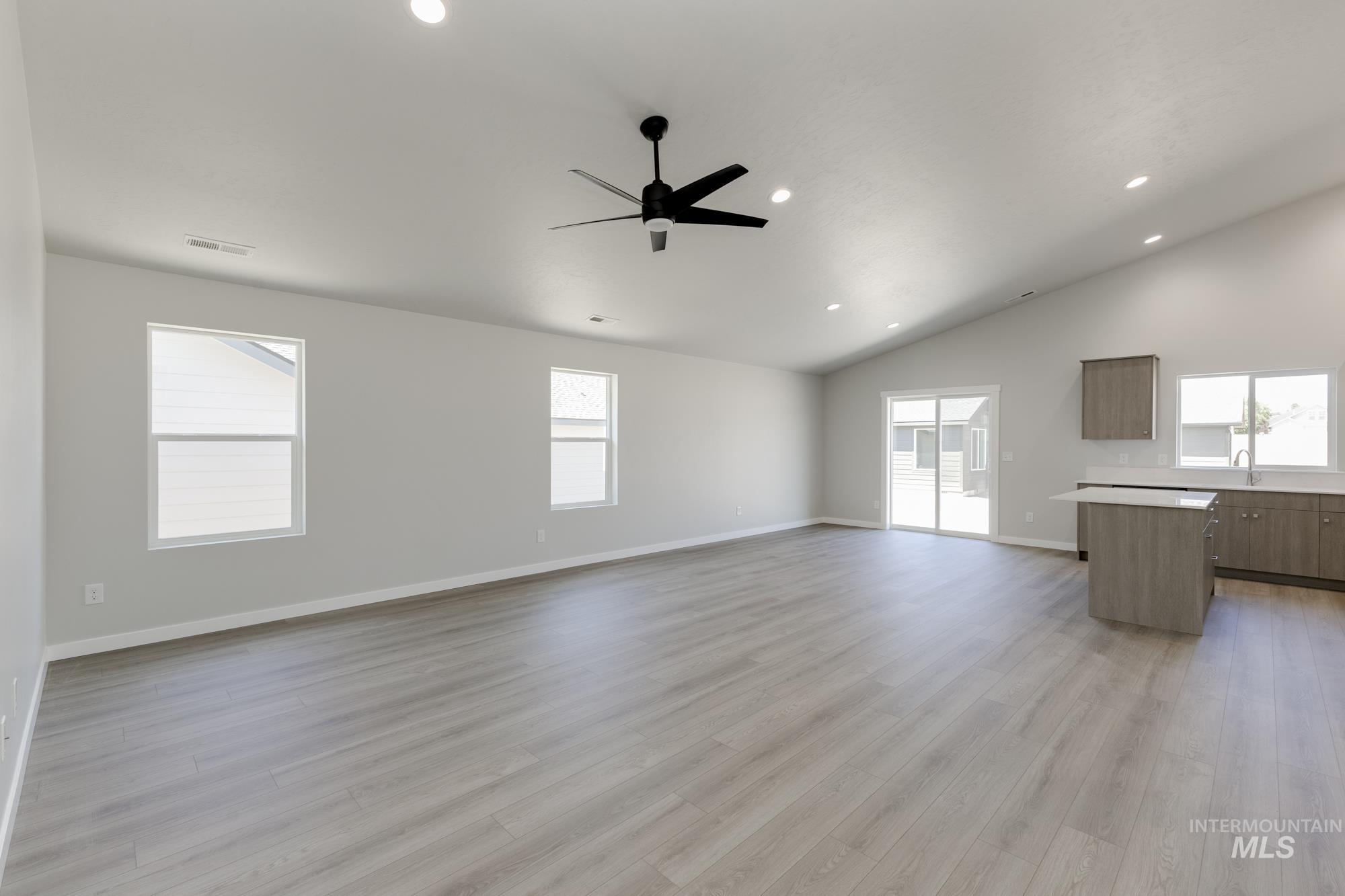 Unfurnished living room with lofted ceiling, ceiling fan, light wood-type flooring, and recessed lighting