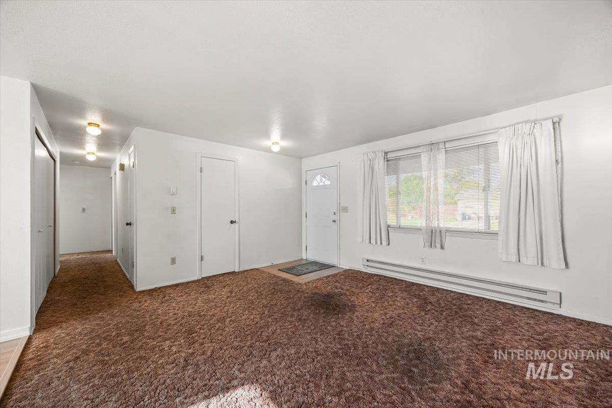 Carpeted entryway featuring a baseboard radiator and baseboards