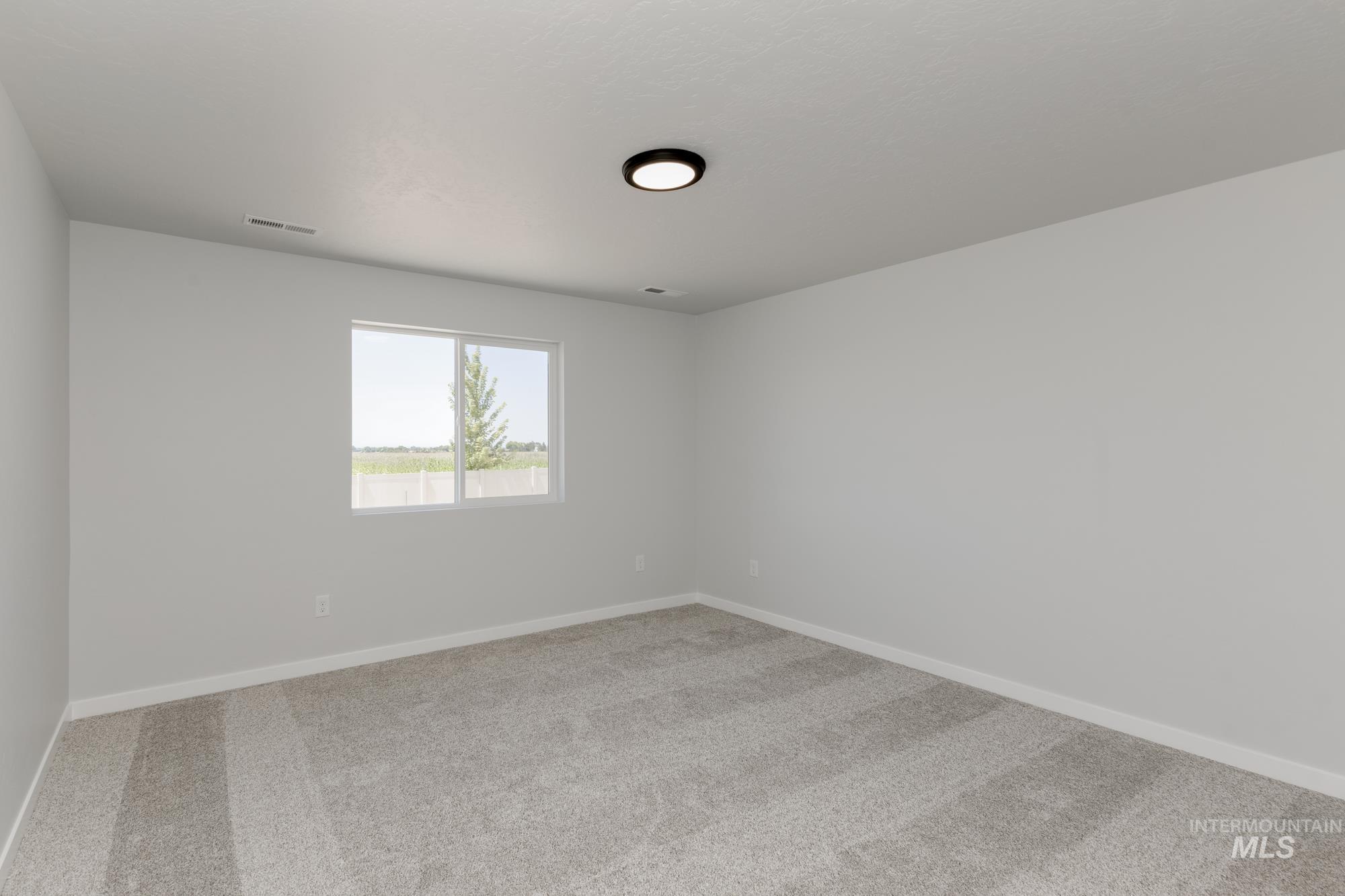 Spare room featuring baseboards and light carpet