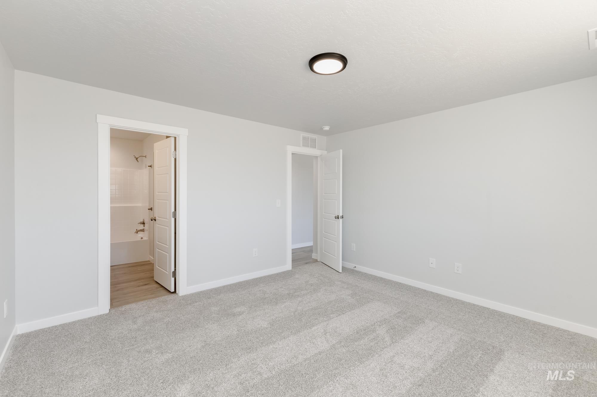 Unfurnished bedroom featuring light carpet and ensuite bath