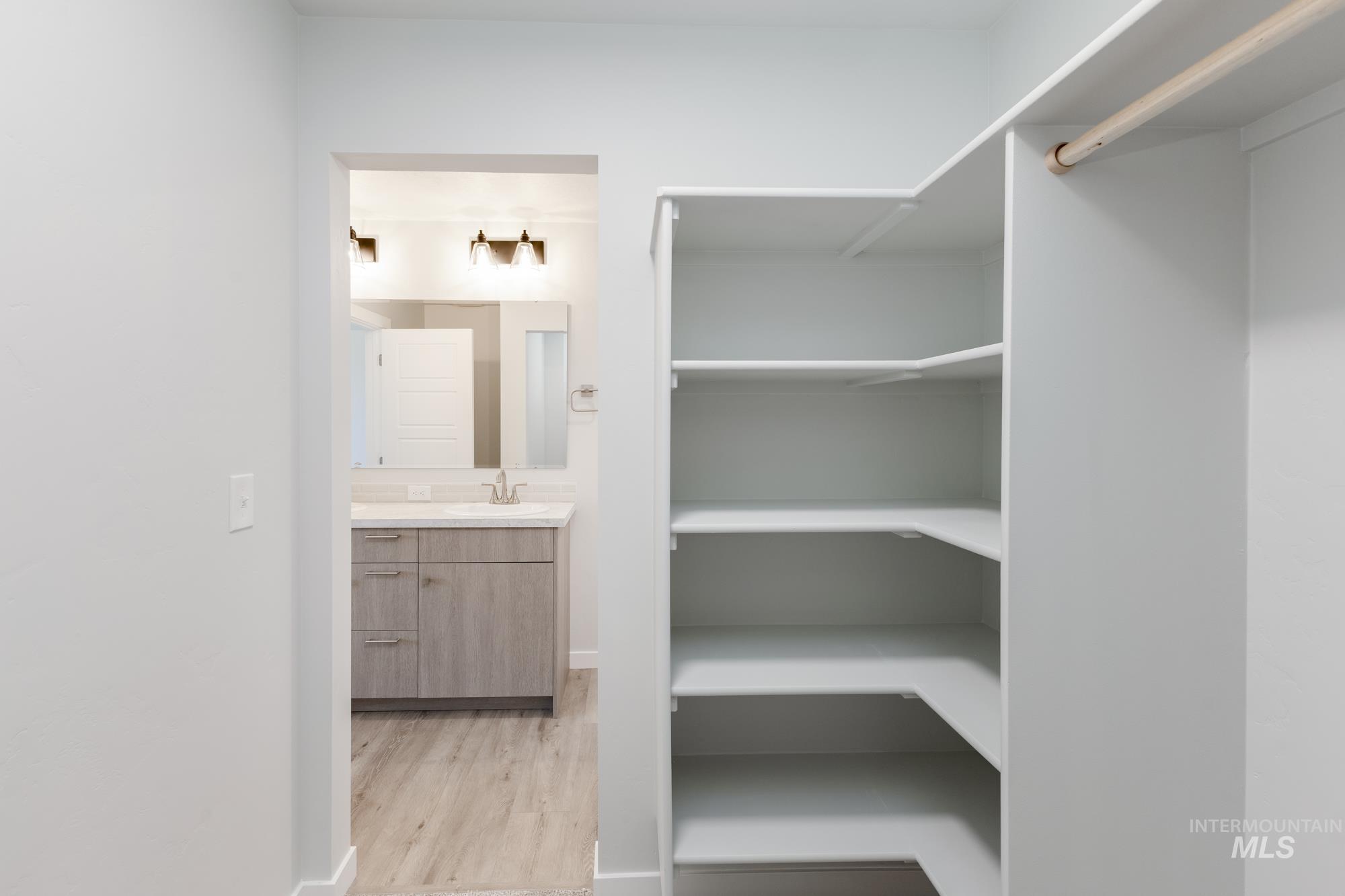 Spacious closet featuring light wood finished floors and a sink