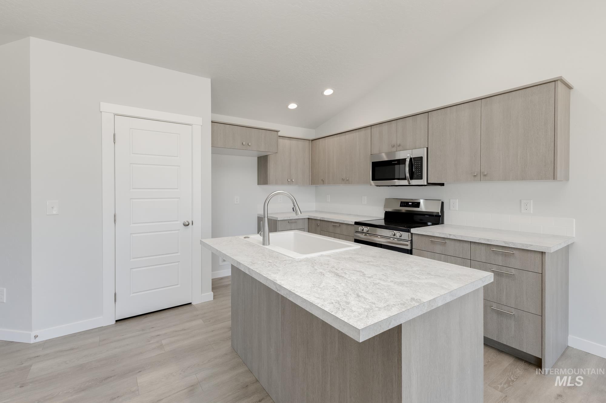 Kitchen with modern cabinets, light brown cabinetry, light countertops, stainless steel appliances, and recessed lighting