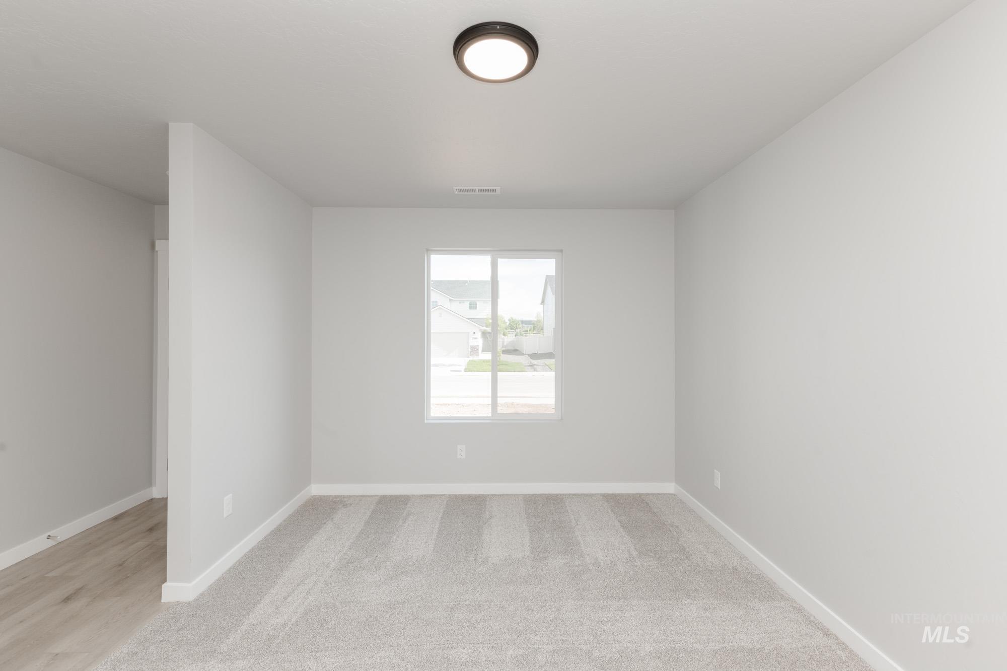 Spare room featuring light carpet and baseboards