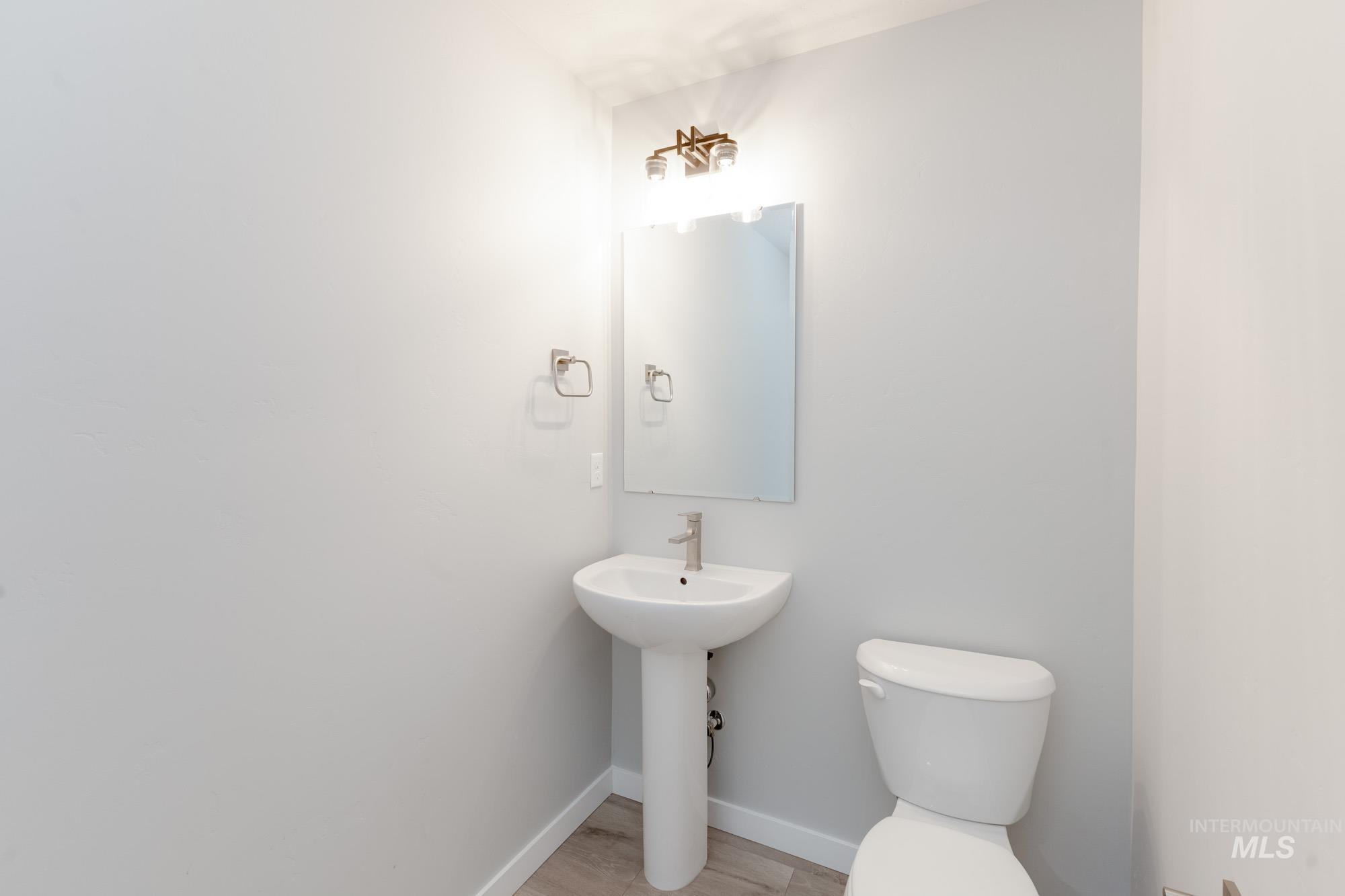Half bath with toilet and wood finished floors