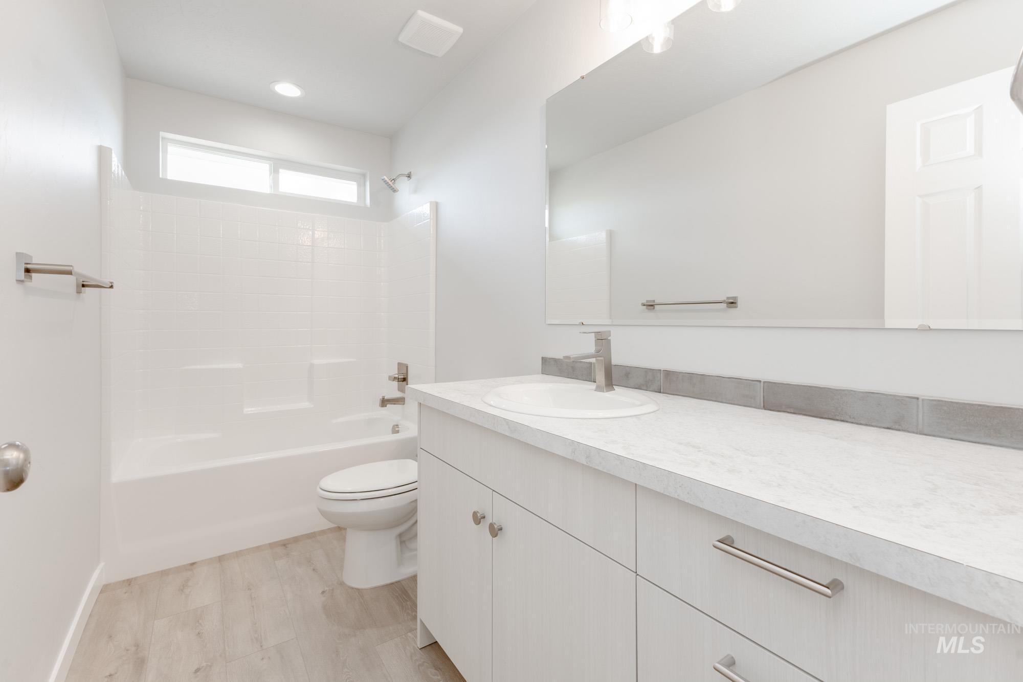 Bathroom with vanity, tub / shower combination, and wood finished floors
