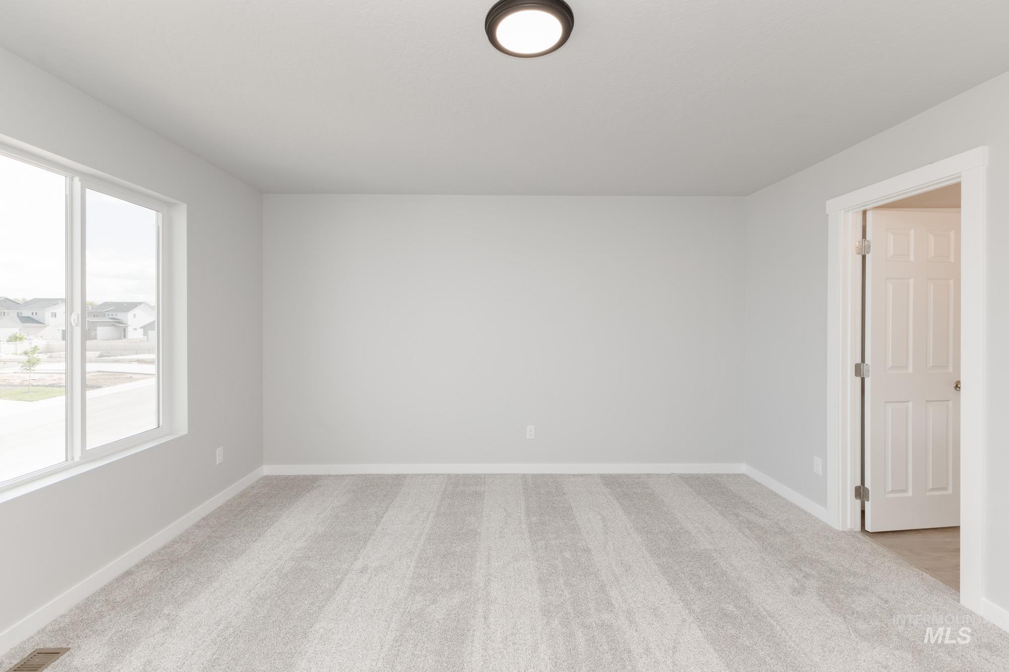 Empty room with light colored carpet and baseboards