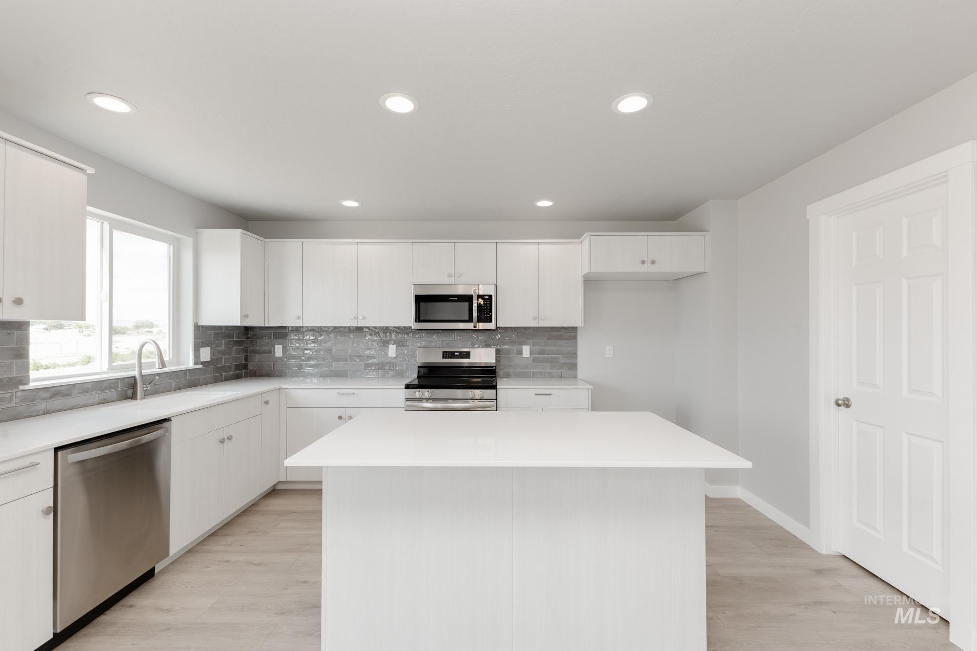 Kitchen featuring stainless steel appliances, light wood-type flooring, a center island, decorative backsplash, and recessed lighting