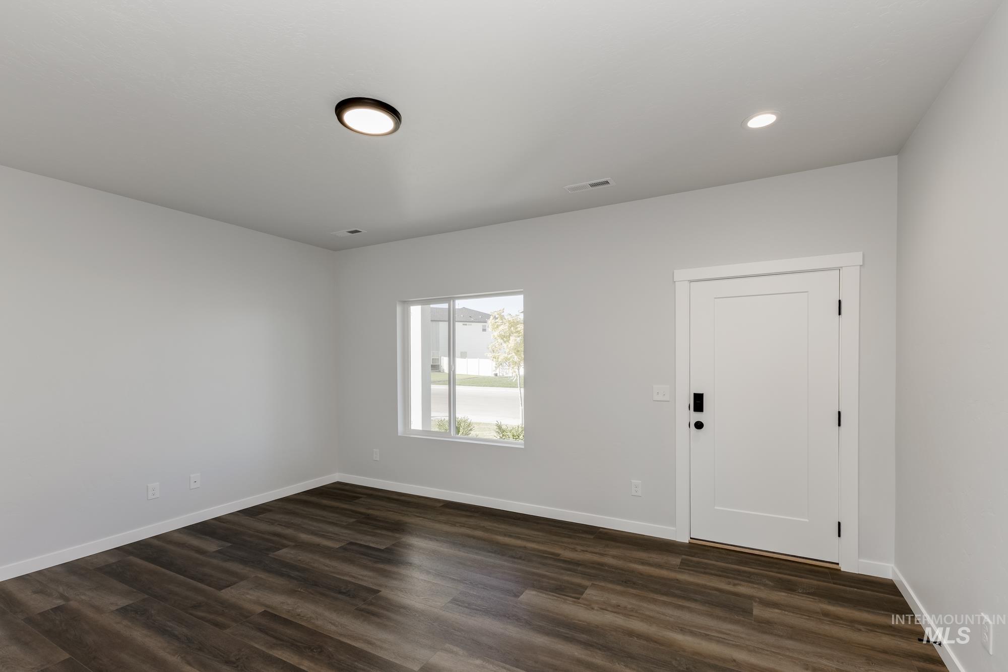 Empty room with dark wood finished floors and recessed lighting