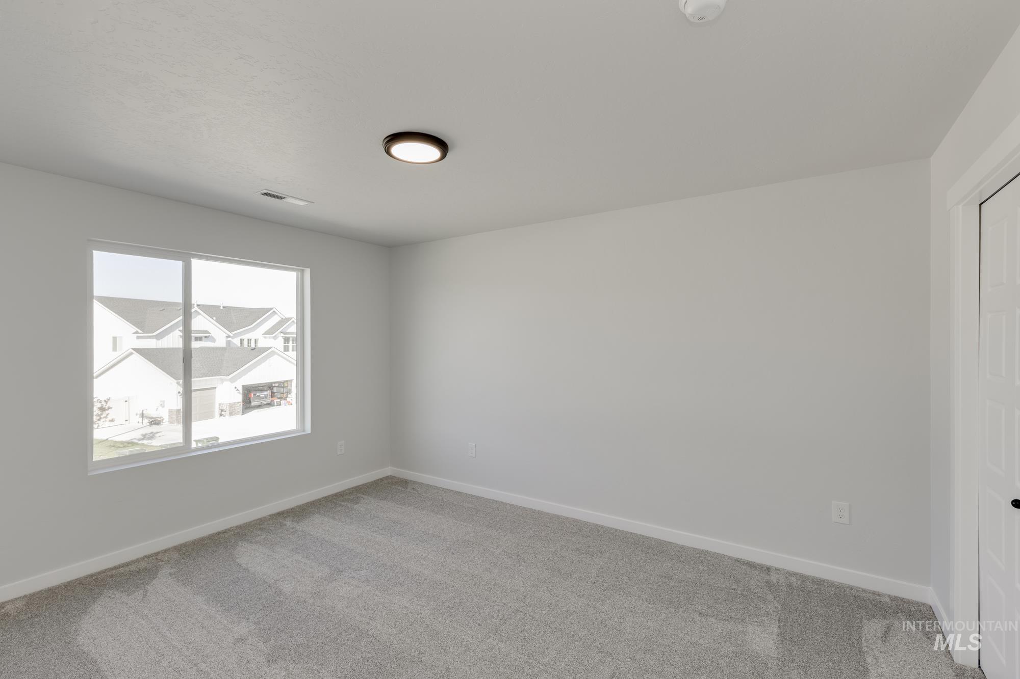 Spare room with baseboards and light carpet