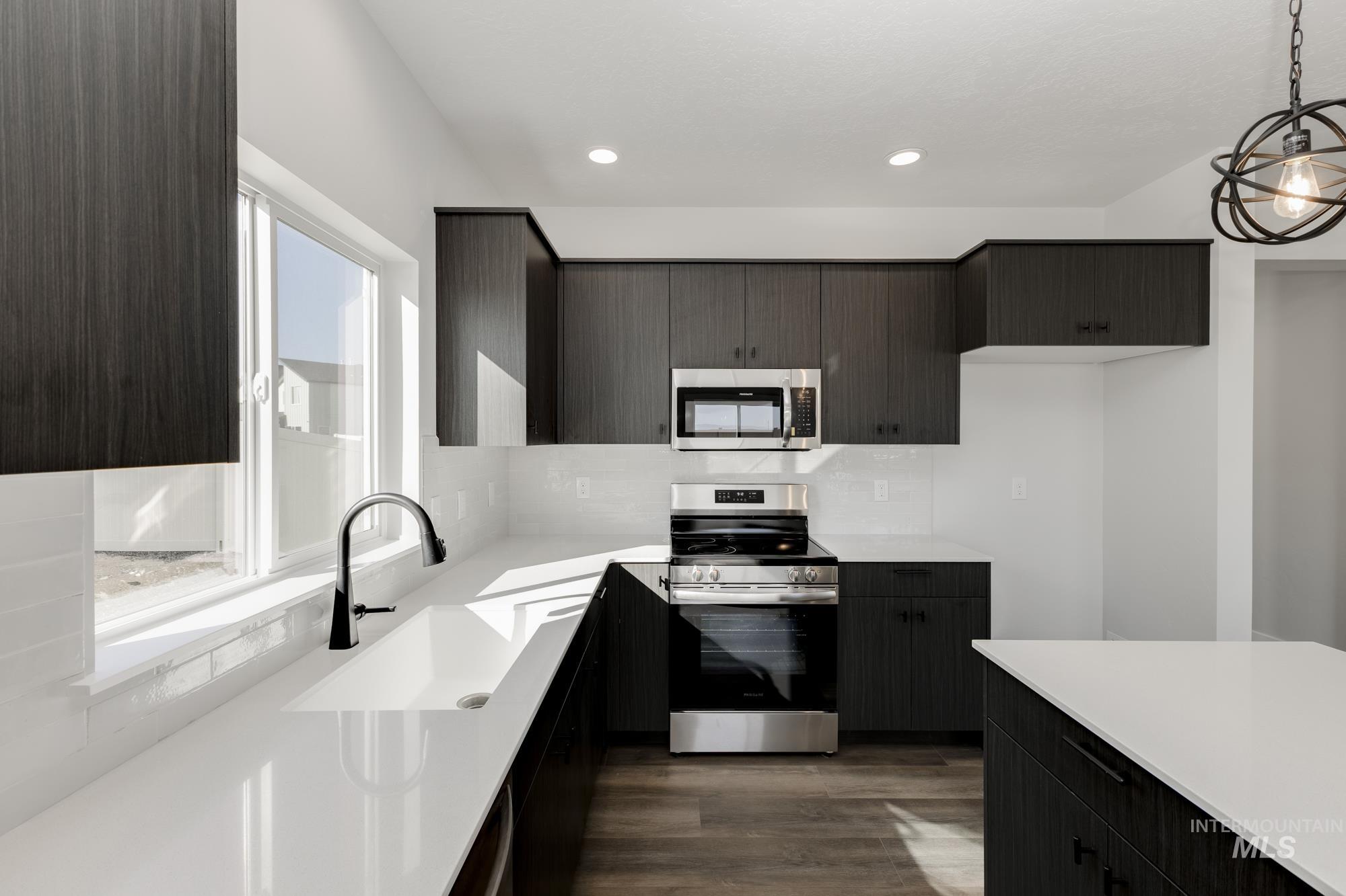 Kitchen with stainless steel appliances, decorative backsplash, dark wood finished floors, decorative light fixtures, and modern cabinets