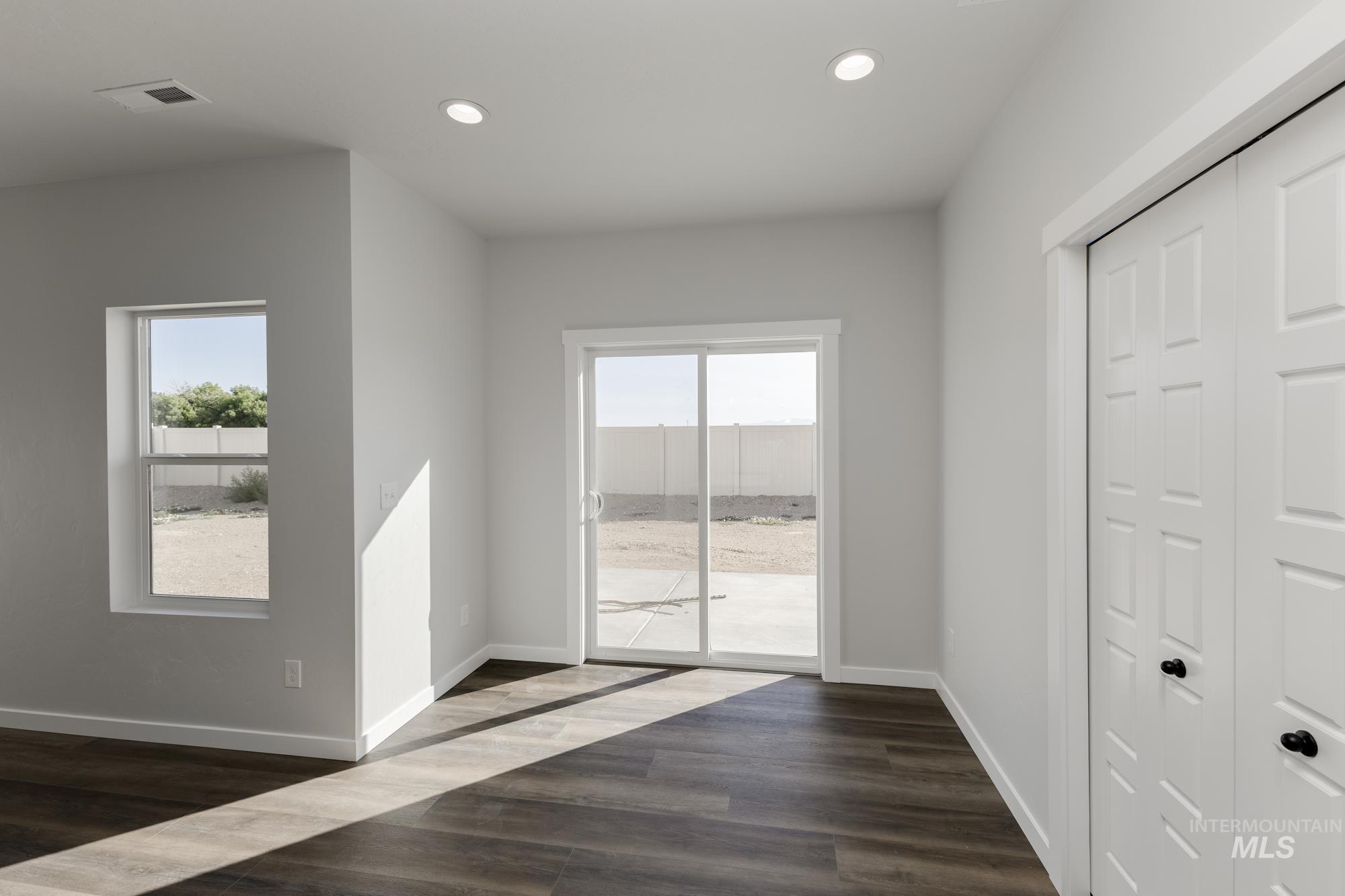 Unfurnished bedroom featuring access to outside, recessed lighting, multiple windows, dark wood finished floors, and a closet