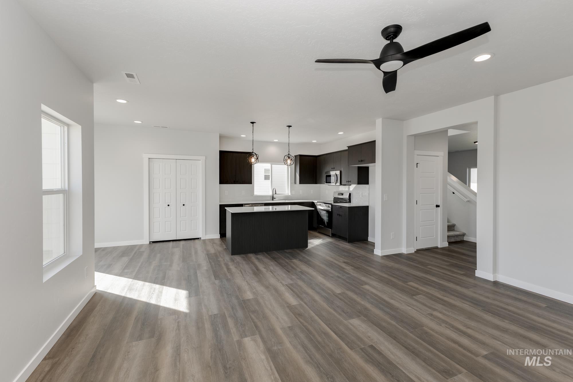 Unfurnished living room with a ceiling fan, dark wood-type flooring, stairway, and recessed lighting