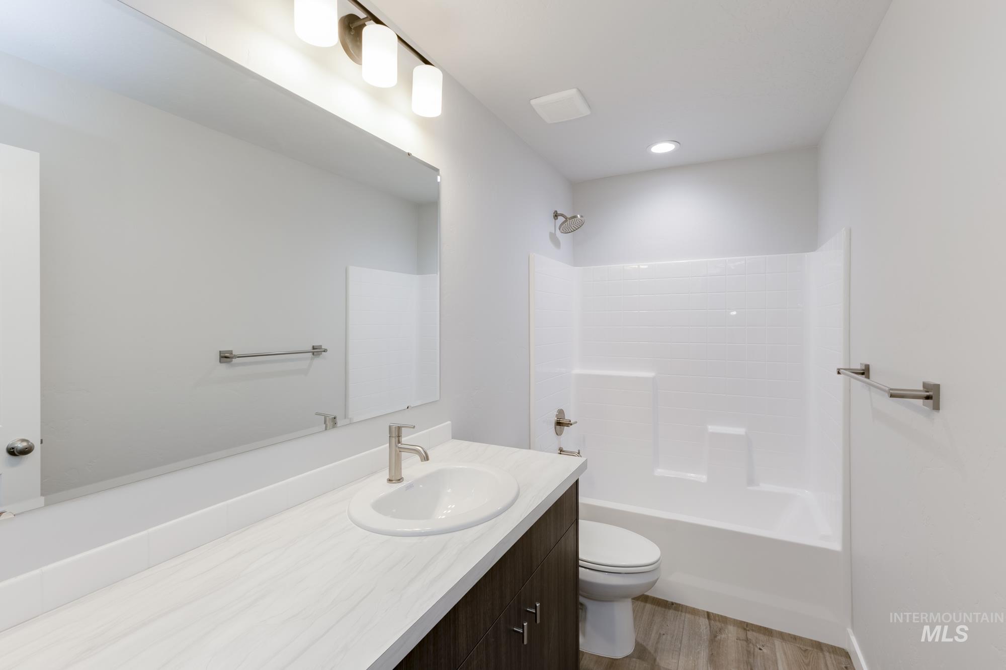 Bathroom featuring vanity,  shower combination, and light wood finished floors