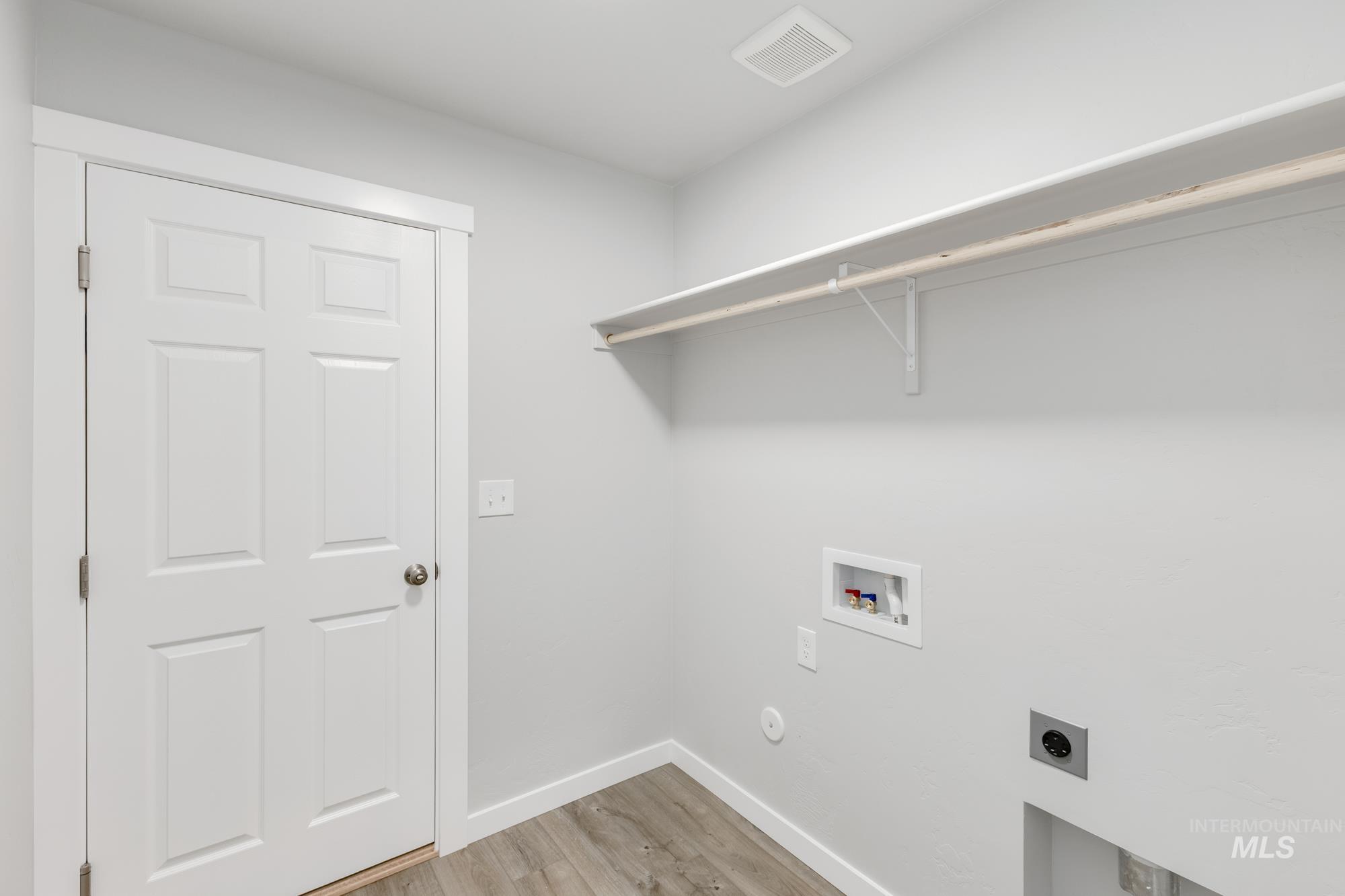 Laundry area featuring hookup for a washing machine, light wood finished floors, and electric dryer hookup