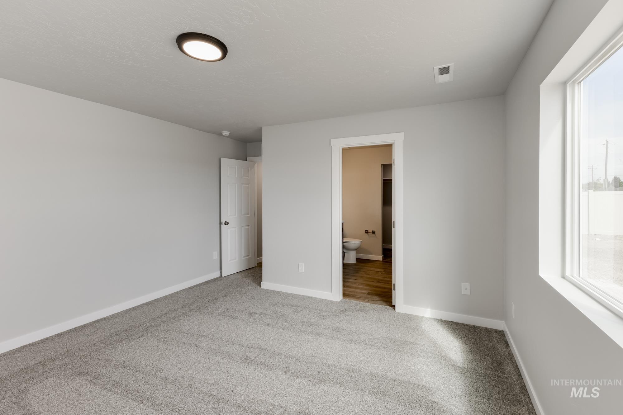 Unfurnished bedroom featuring carpet and ensuite bathroom