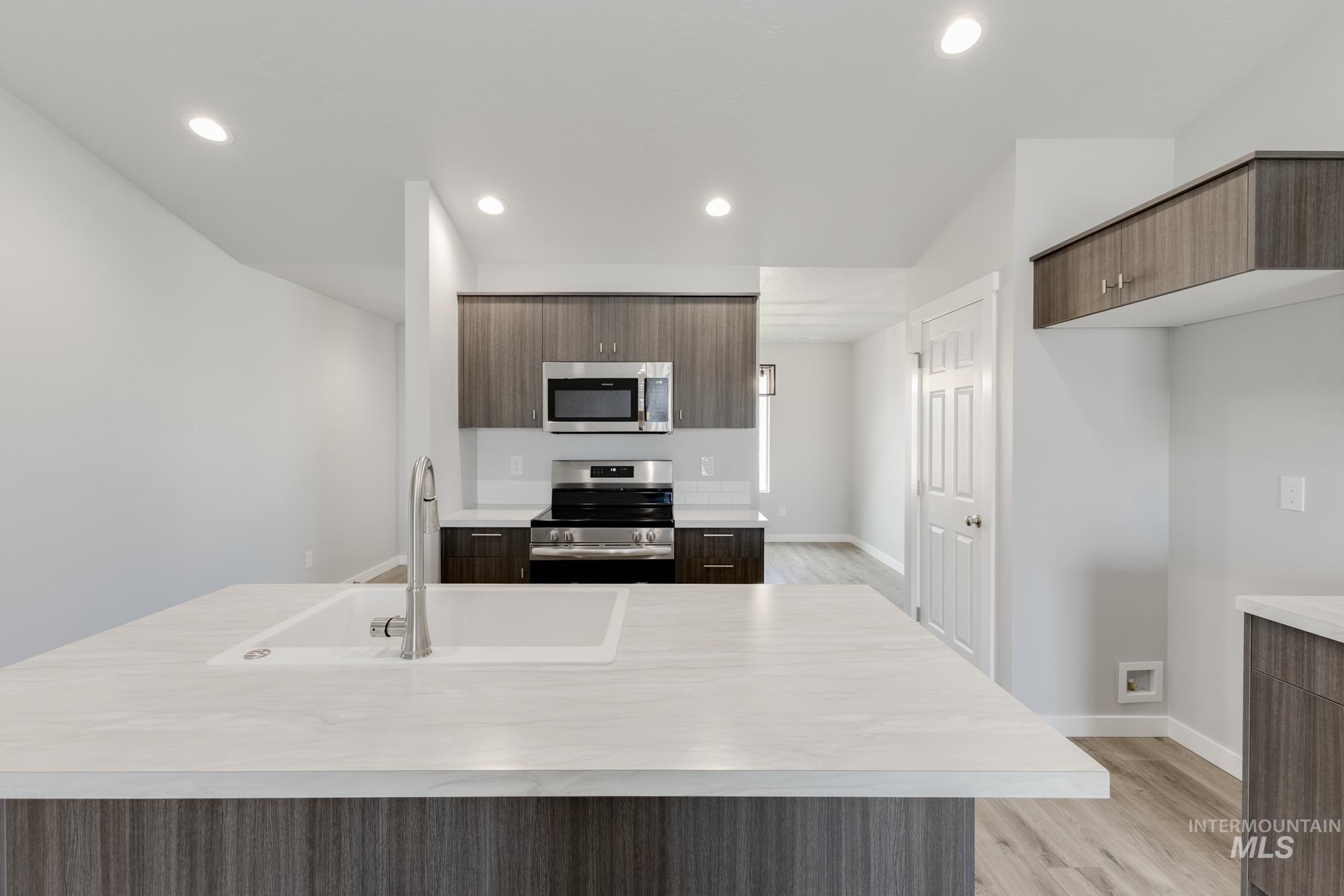 Kitchen with appliances with stainless steel finishes, light countertops, modern cabinets, and recessed lighting