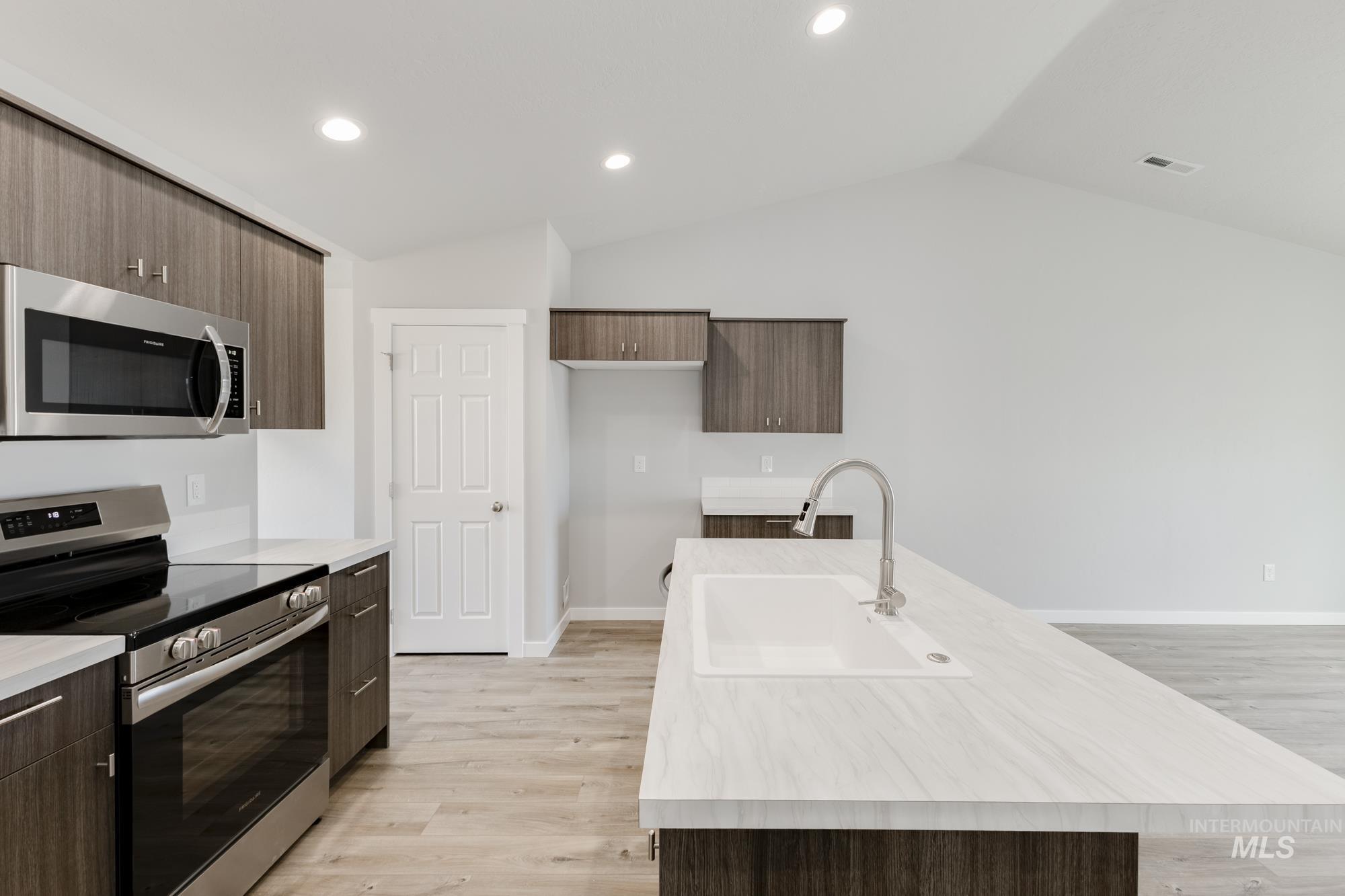 Kitchen featuring appliances with stainless steel finishes, light wood-type flooring, dark brown cabinetry, modern cabinets, and recessed lighting