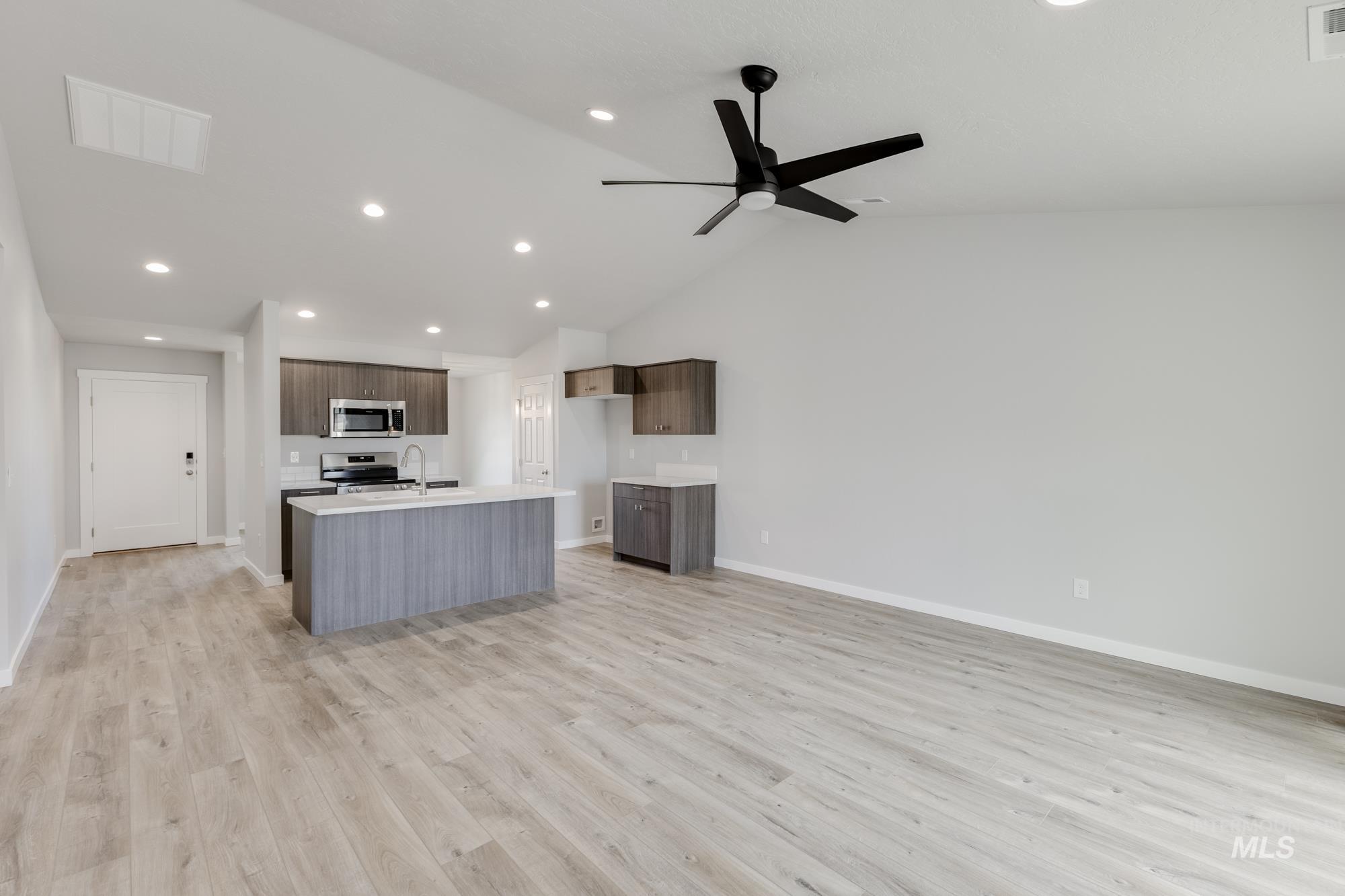 Kitchen featuring open floor plan, light wood-type flooring, an island with sink, vaulted ceiling, and recessed lighting