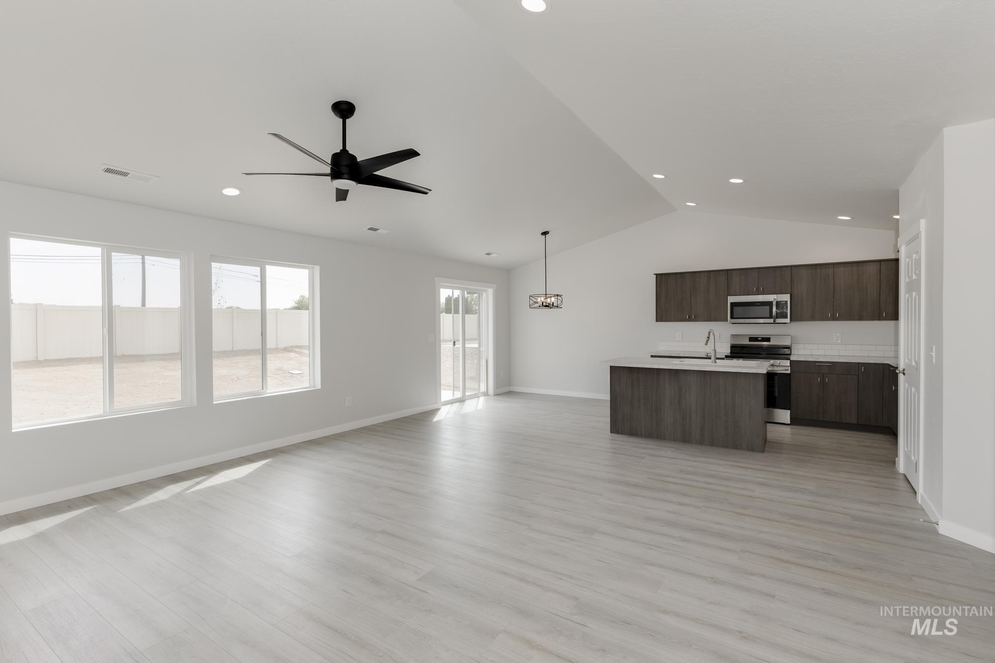 Kitchen featuring open floor plan, light countertops, light wood finished floors, a kitchen island with sink, and stainless steel appliances