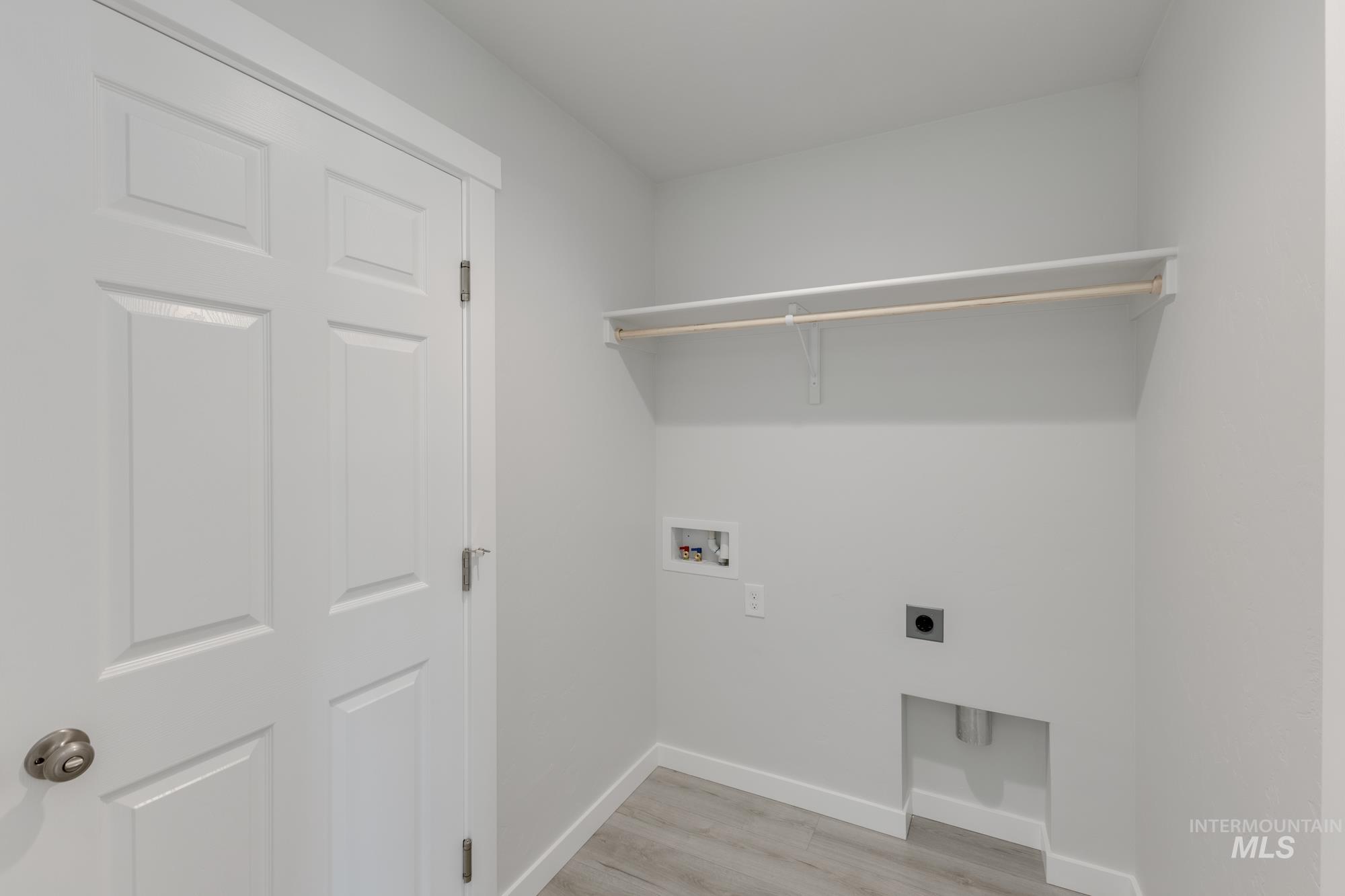 Laundry area with light wood-style floors, electric dryer hookup, and washer hookup