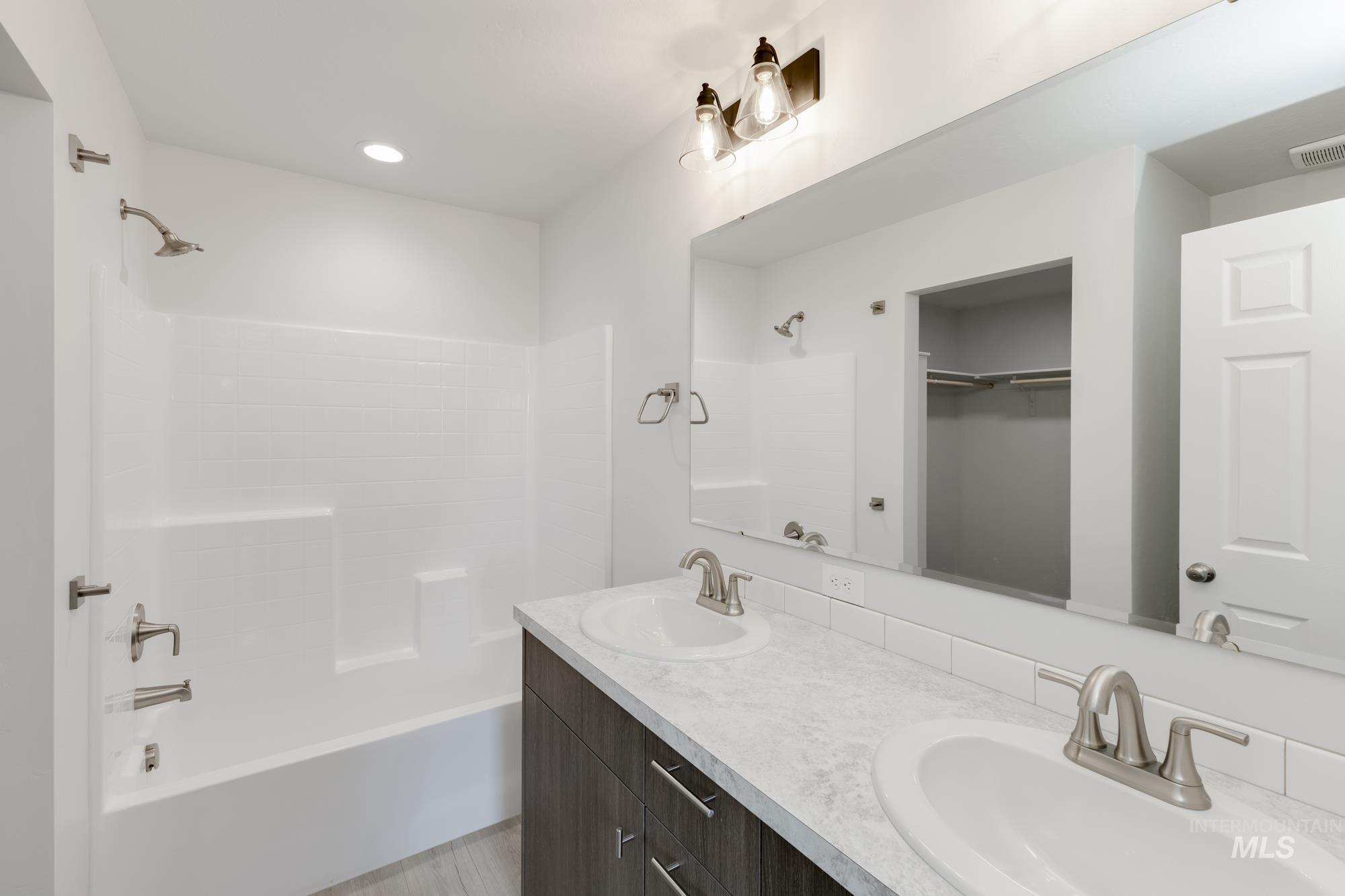 Bathroom with  shower combination, double vanity, a walk in closet, and recessed lighting